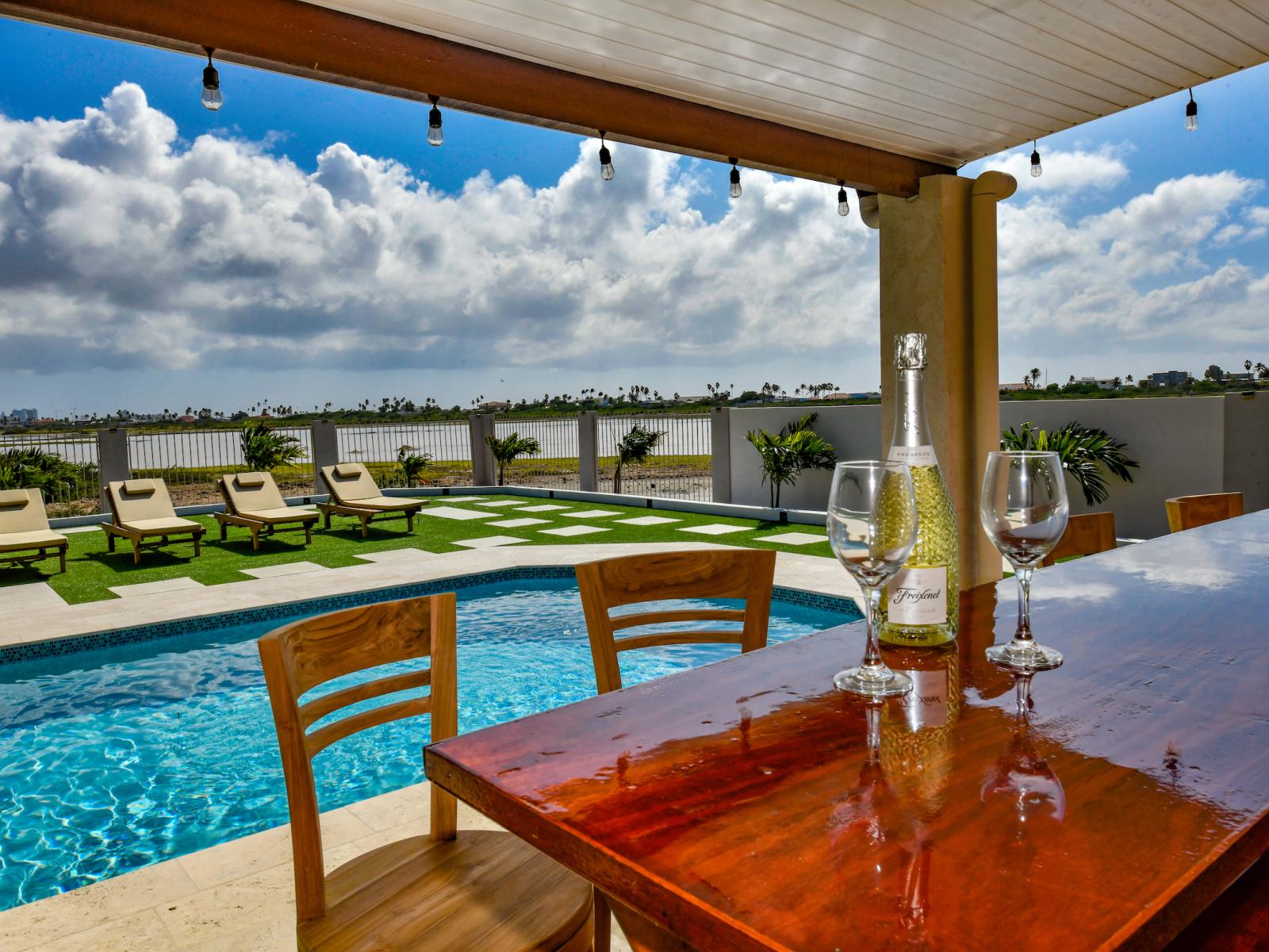 Elite outdoor dining area of the 3BR House in Noord Aruba - Beautiful 6 persons dining - Majestically decored space with refreshing Atmosphere - Superbly sunbathed space with umbrella shade - Outstanding pool facing dining area - Beautiful views