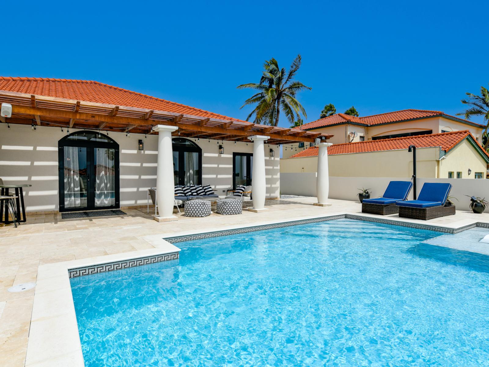 Luxury pool area of the Villa in Noord Aruba - Lush and refreshing environment - Cozy beach chairs available - Beautifully sunbathed space makes the soul peaceful - Experience the comfort at the best