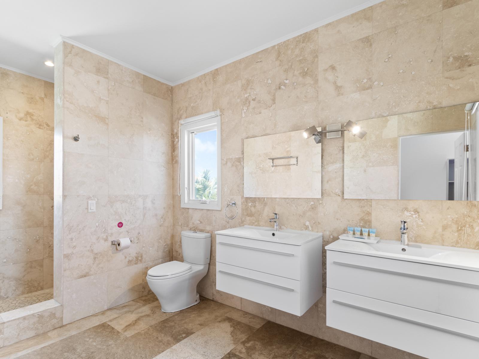 Exquisite Bathroom of the Villa in Noord Aruba - Beautiful Vanity with large size wall mirror - Sufficient storage space - Neat and clean toilet seat - Availability of all bathroom amenities - Stunning shower area