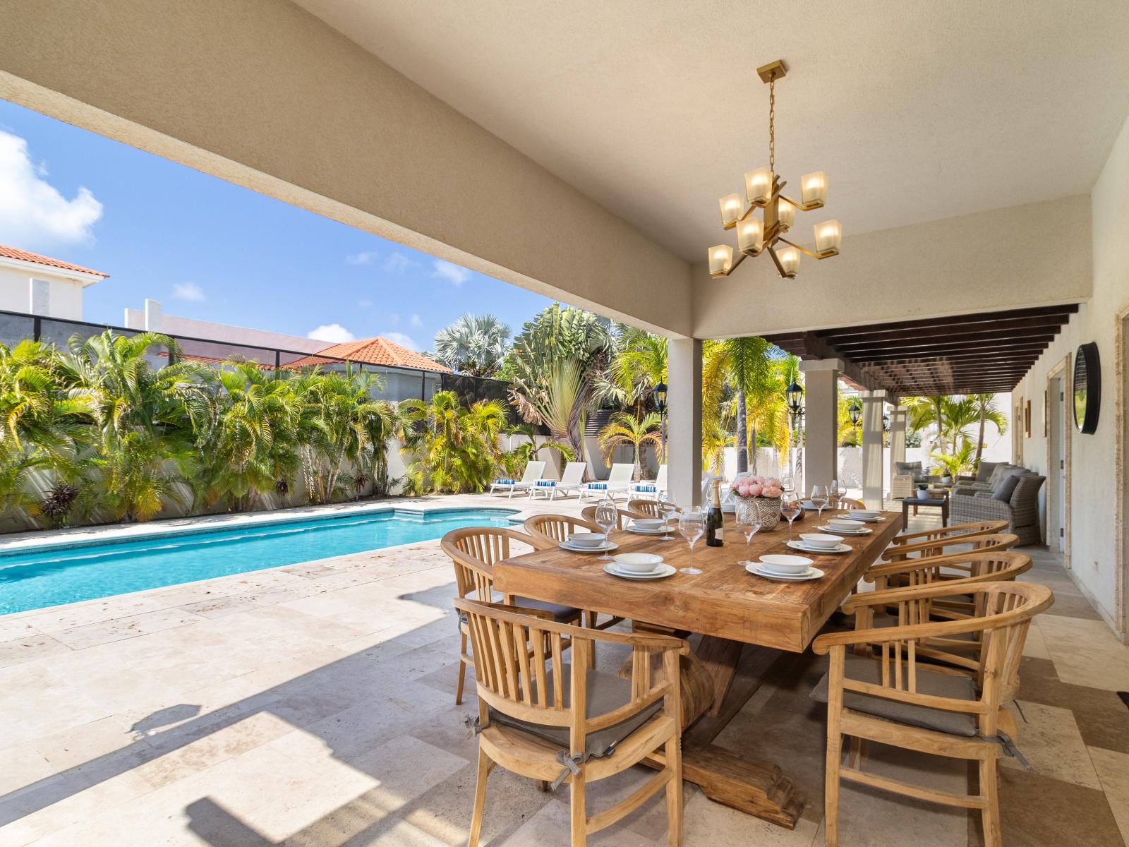 A spacious outdoor dining table located next to the pool.