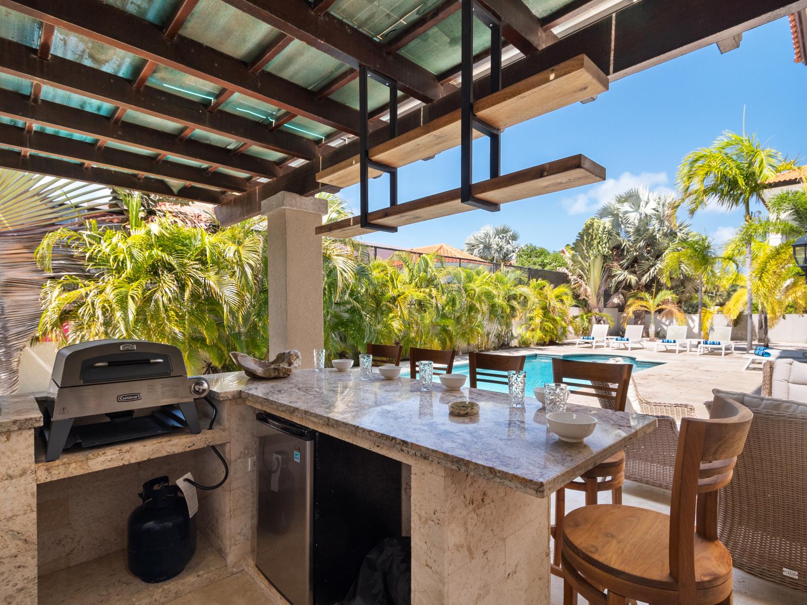 The outdoor kitchen features a bar area complete with high chairs, ideal for enjoying drinks and meals with a view.