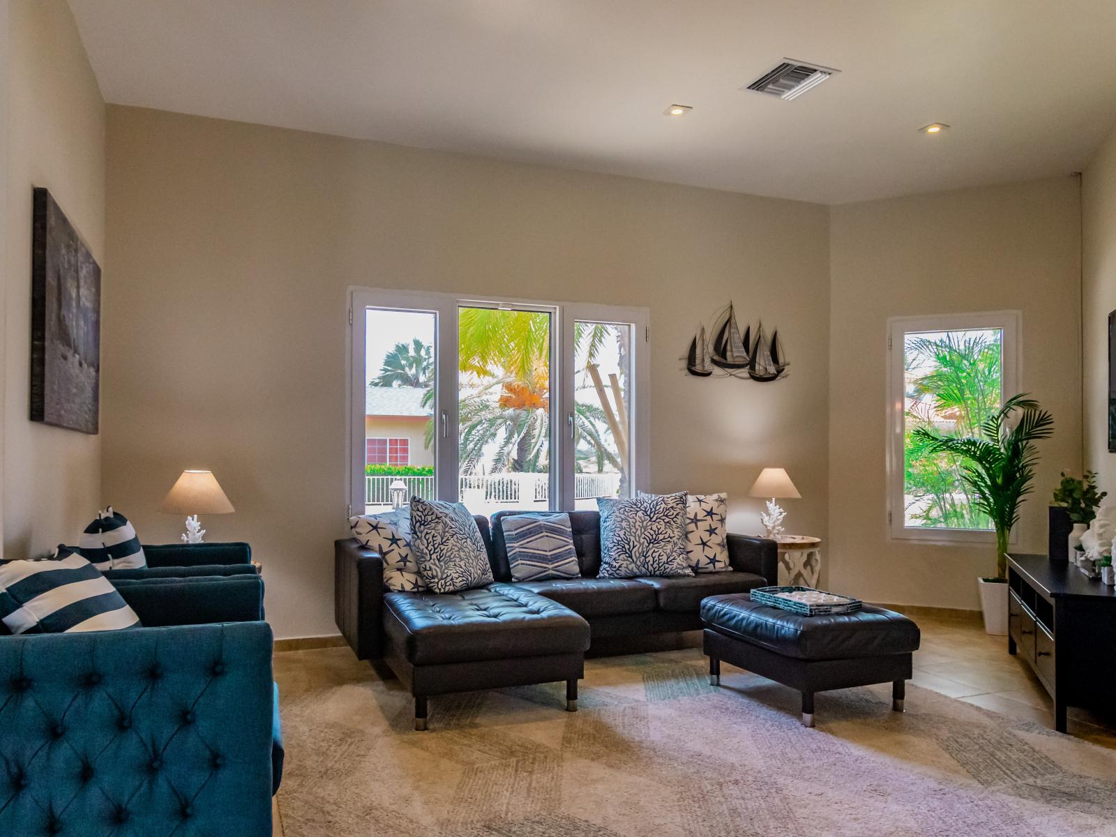 Luxury living area of the villa in Noord, Aruba - Cosy sofas - Beautifully located large windows with mesmerizing views - Elite ambiance - Beautifully decored with wall paintings and majestic table lamps - Availability of TV and Netflix