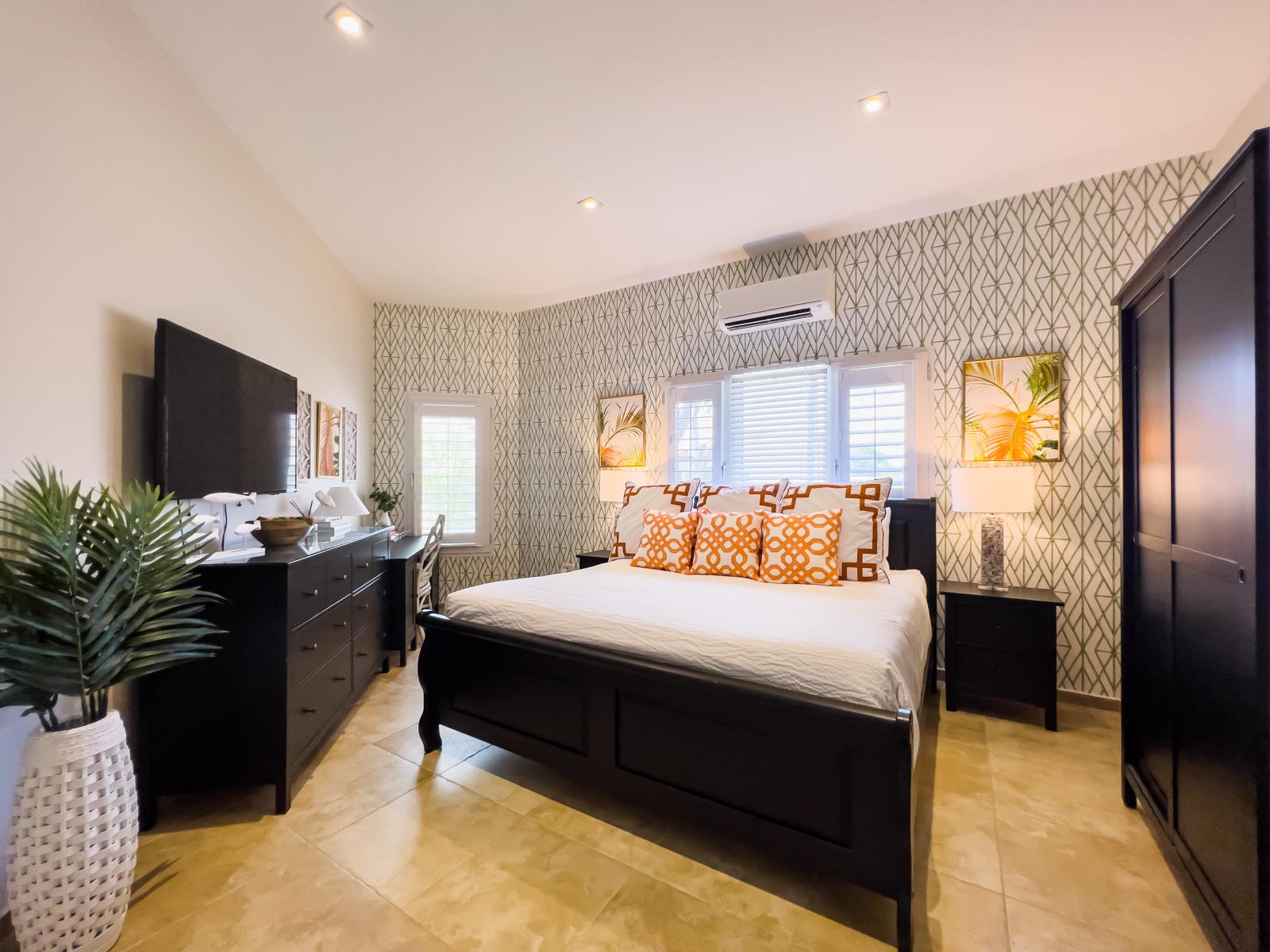 Opulent bedroom of the villa in Noord, Aruba - Comfy king size bed - Elegantly designed room beautifully decored with aesthetic wallpaper and paintings - Majestic table lamps - Neat and clean linen with soft pillows - Availability of TV and Netflix