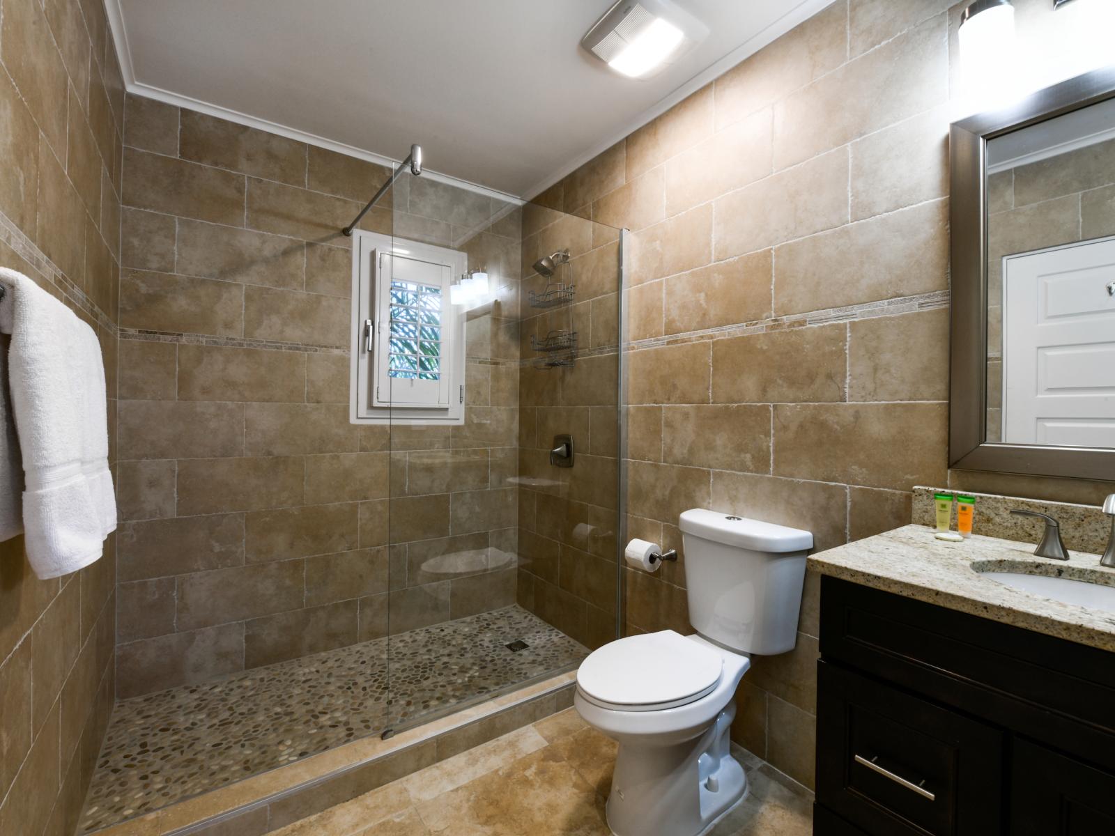 Classy Bathroom of the villa in Noord, Aruba - Neat and clean toilet seat - Availability of all bathroom amenities - Beautiful large vanity with large size mirror and twin sinks - Elegant lighting - Stunning separate glass shower area