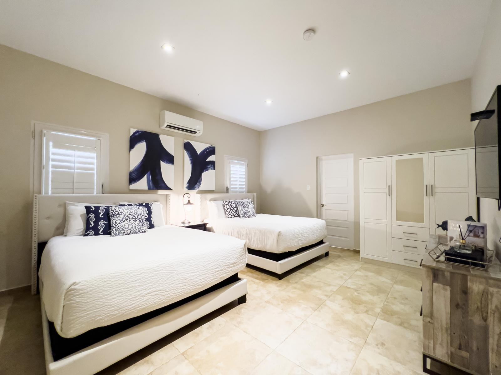 Lavish bedroom of the villa in Noord, Aruba - Comfy 2 king size bed - Elegantly designed room beautifully decored with aesthetic wall paintings - Majestic table lamps - Window at bed back that makes room bright - Availability of TV and Netflix