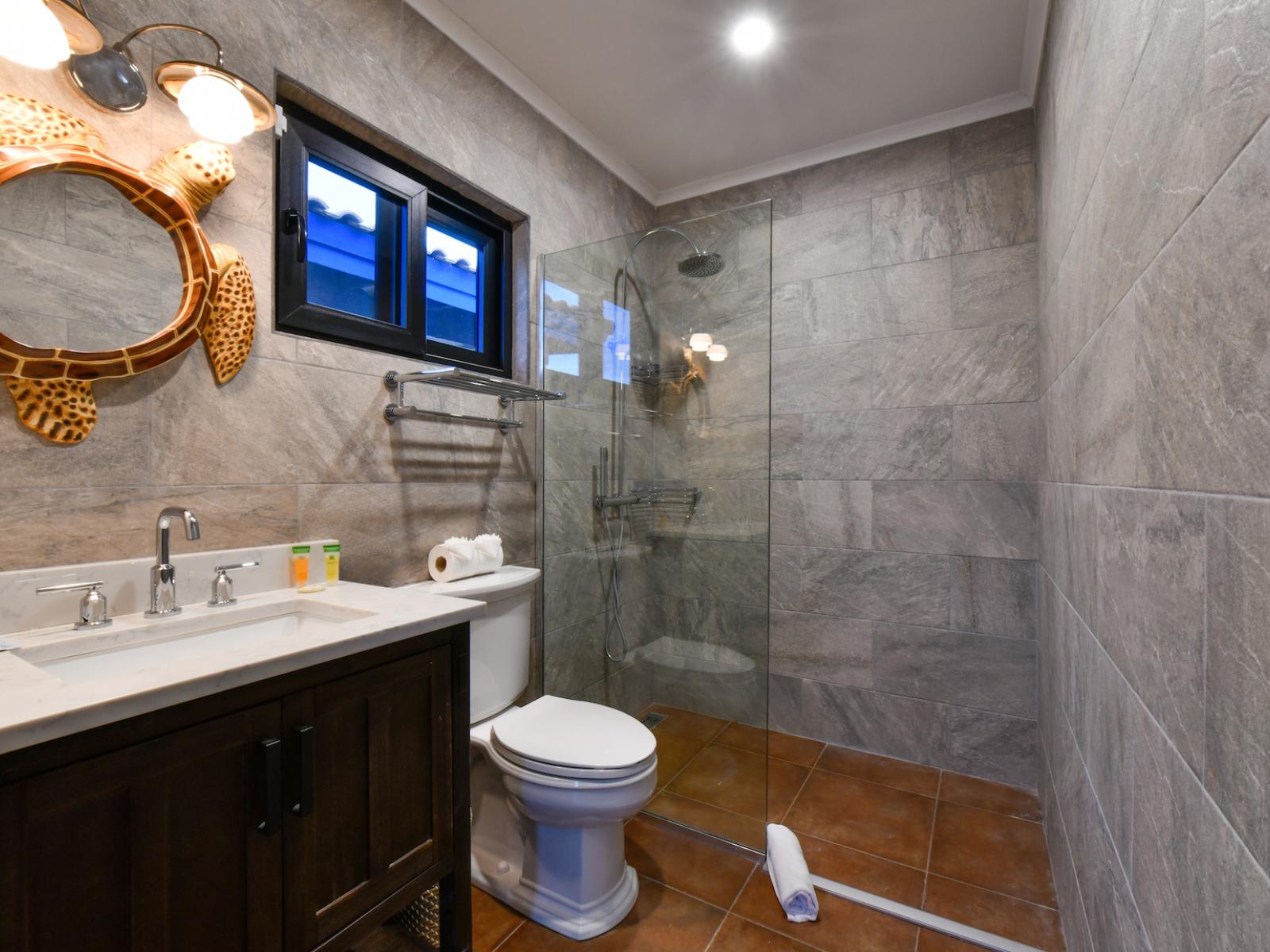 Toney Bathroom of the 4BR House in Noord Aruba - Chic design featuring a sleek vanity and upscale lighting - Seamless design featuring a glass-enclosed shower for a modern touch - Spacious layout offering a sense of luxury and comfort