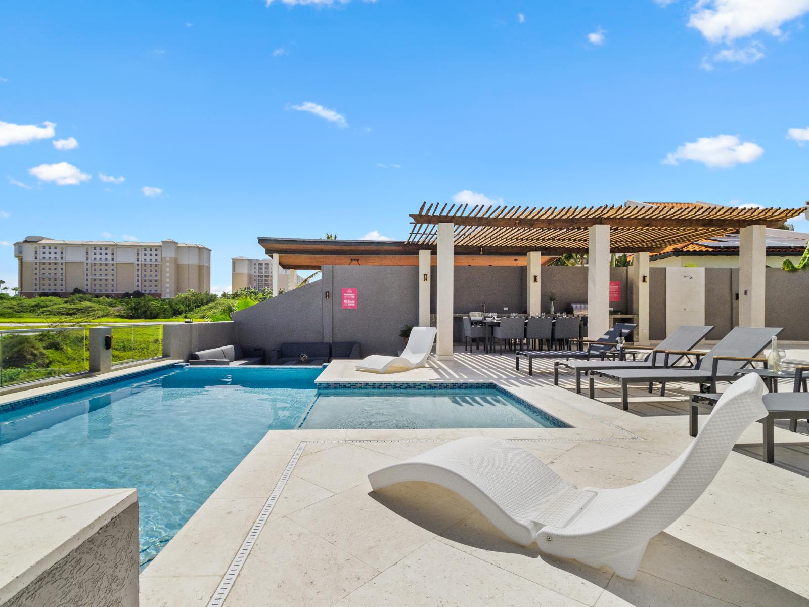 Refreshing Pool Area of the Villa in Noord Aruba  - Pool area with Marriott hotel in the back - Dive into a refreshing poolside escape - Lounge in tranquility by the sparkling waters - Modern lounge chairs for ultimate relaxation