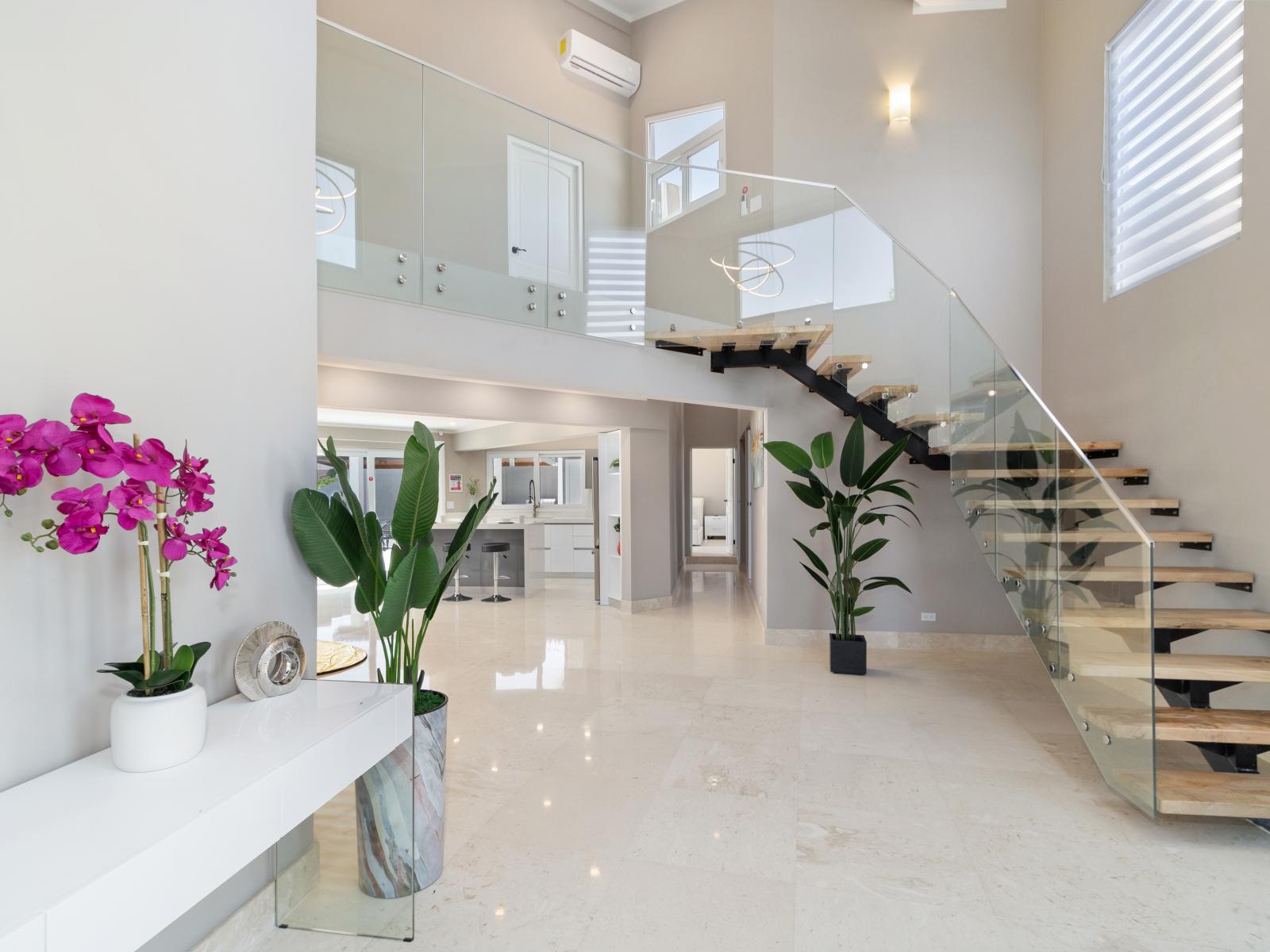 Spacious Foyer and Lush Staircase of the Villa in Noord Aruba -  Luxurious fixtures and finishes - High-end materials such as marble and brushed nickel accents - Lush greenery enhances every corner