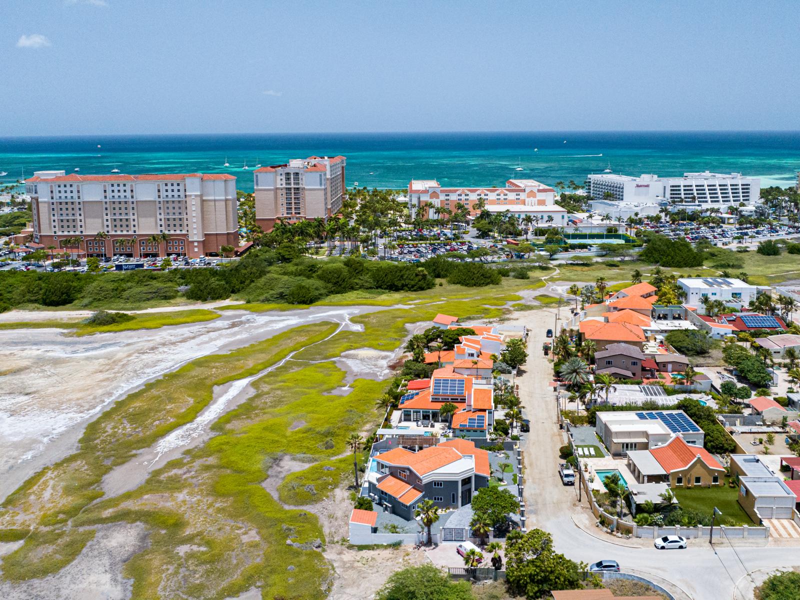 An Aerial Tapestry: This captivating image weaves together the colorful tapestry of our neighborhood, featuring the majestic Hooiberg, tranquil saliña, bustling high-rise area, and the iconic Marriott hotels, offering a panoramic glimpse into the diverse b