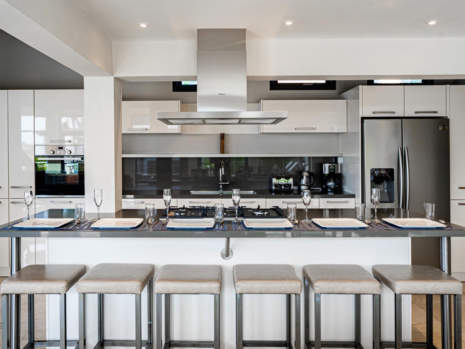 Modern kitchen of the Villa in Noord Aruba - Integrated appliances for a seamless and stylish appearance - Open concept connecting the kitchen to the dining and living area - Functional island for additional workspace