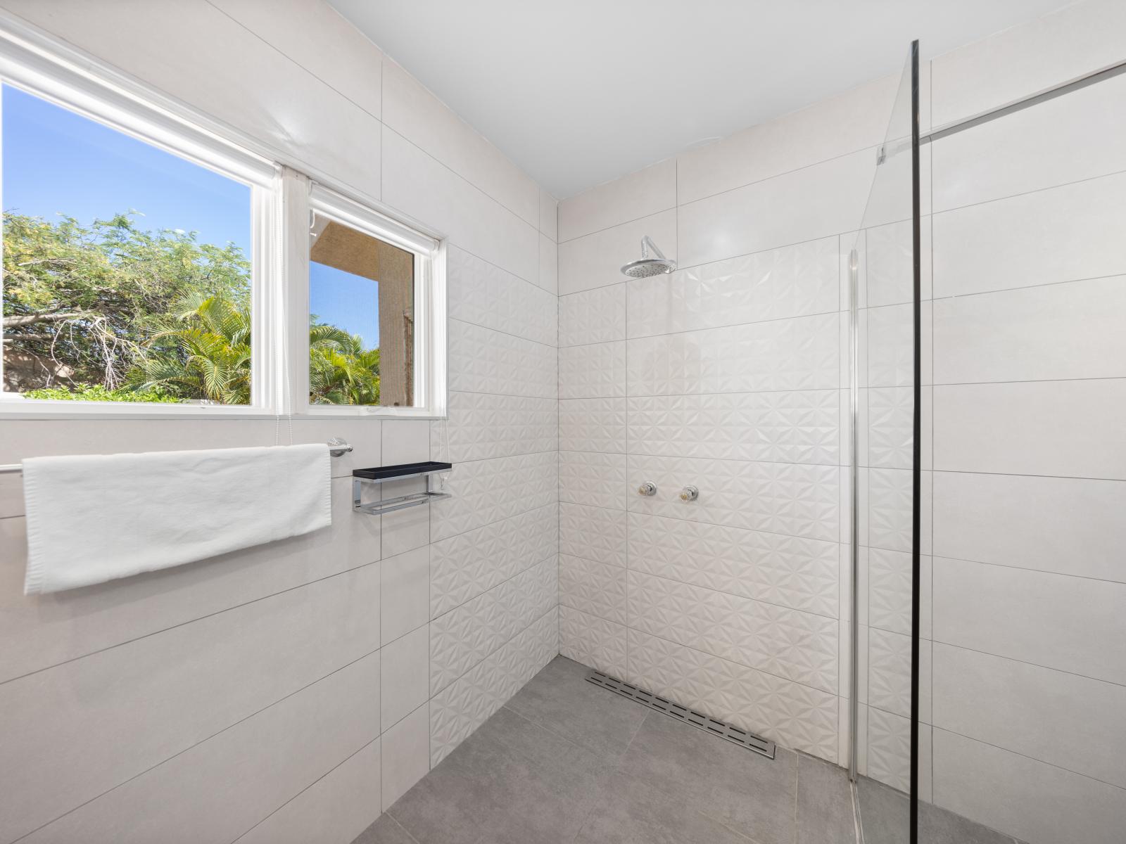 Indulge in the modern elegance of Bathroom 2's walk-in shower. Step into this spacious sanctuary where sleek design meets ultimate comfort for a rejuvenating experience.