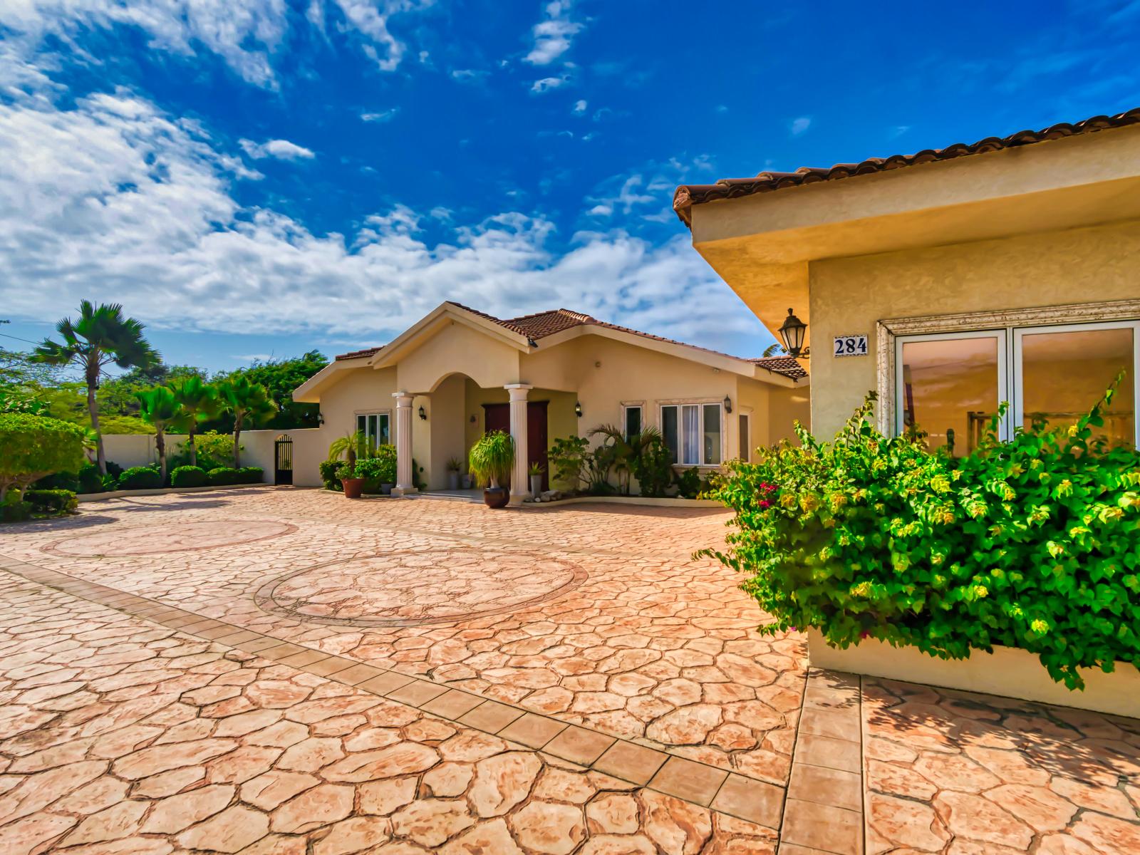 Welcome to the front of our villa, where timeless elegance meets tropical charm. With lush landscaping and inviting architecture, this picturesque setting sets the stage for a truly unforgettable Aruban escape.