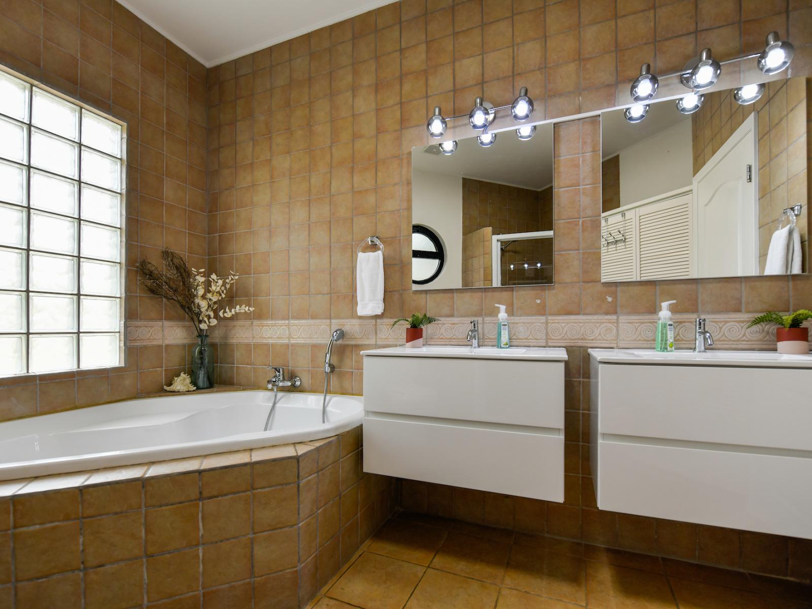 Classy Bathroom of the villa in Noord, Aruba - Neat and clean toilet seat - Availability of all bathroom amenities - Beautiful large vanity with large size mirror and twin sinks - Elegant lighting - Stunning separate bathtub with shower