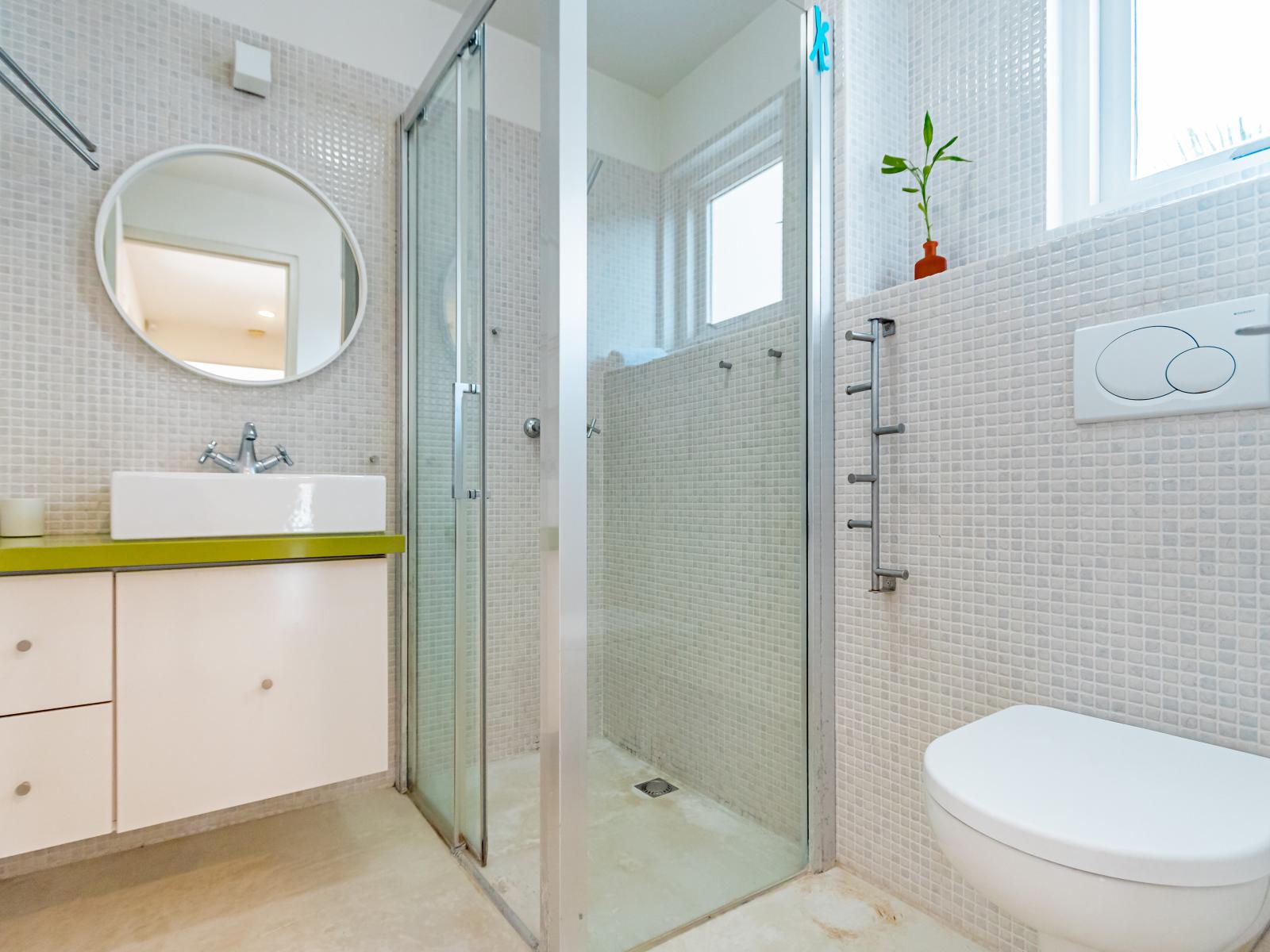 Polished Bathroom of the Home in Santa Cruz Aruba - Walk in shower - Chic Vanity with mirror - Seamless integration of natural elements, like plants for a fresh touch