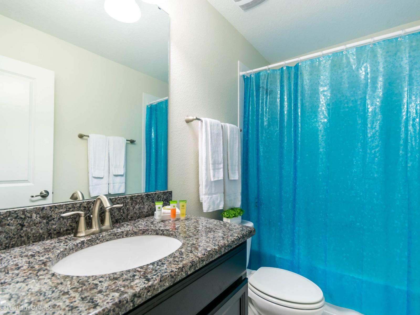 Bathroom of the Home in Davenport Florida - The toilet and bath create a private oasis to refresh and rejuvenate - Modern fixtures, a soothing ambiance, and thoughtful design - It provides a comfortable space for personal care and relaxation