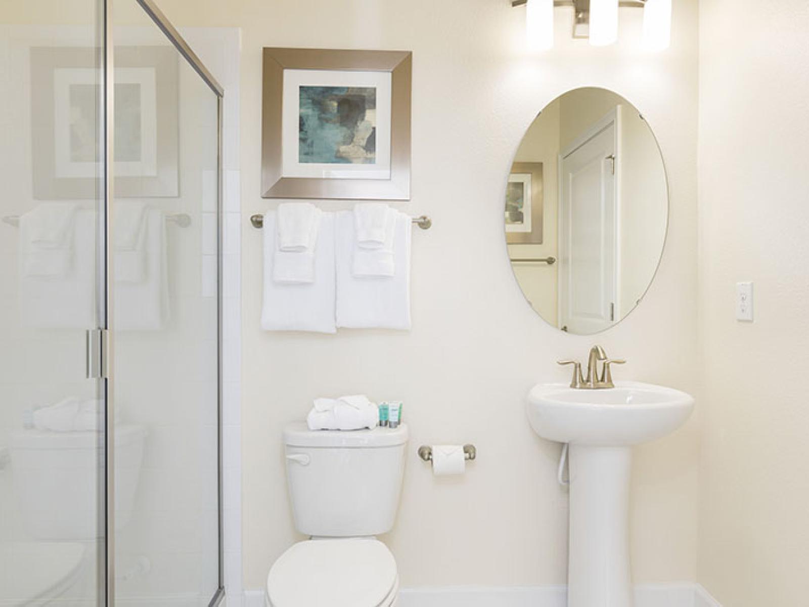 Elegant Bathroom of the Home in Davenport Florida - Glass-enclosed shower Area - Stylish sink and round mirror - Sophisticated color palette creating a serene ambiance