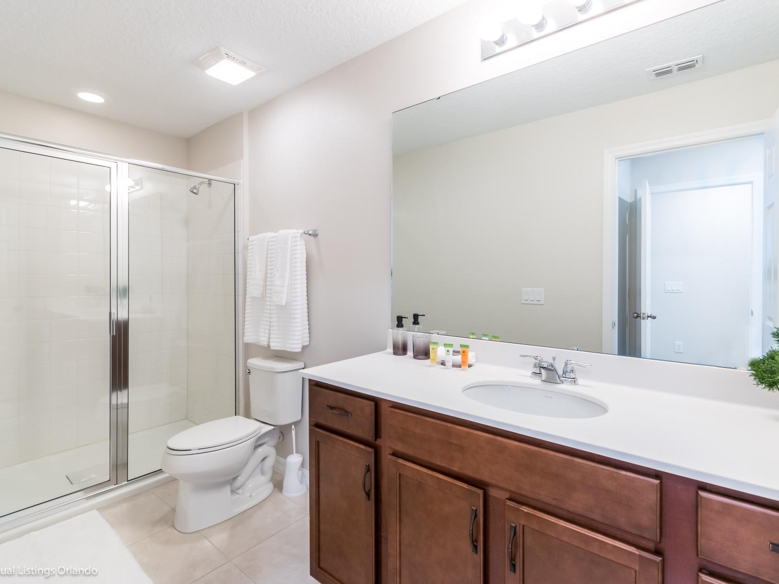 - Exclusive Bathroom of the apartment in Kissimmee - Beautiful Vanity with large size wall mirror - Sufficient storage space - Neat and clean toilet seat - Availability of all bathroom amenities - Stunning glass cabin shower area