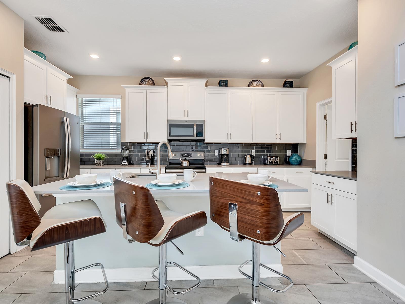 Modern kitchen of the Home in Davenport Florida - High-end appliances and luxurious finishes for a sophisticated touch. - High Chairs and breakfast bar for casual dining and socializing