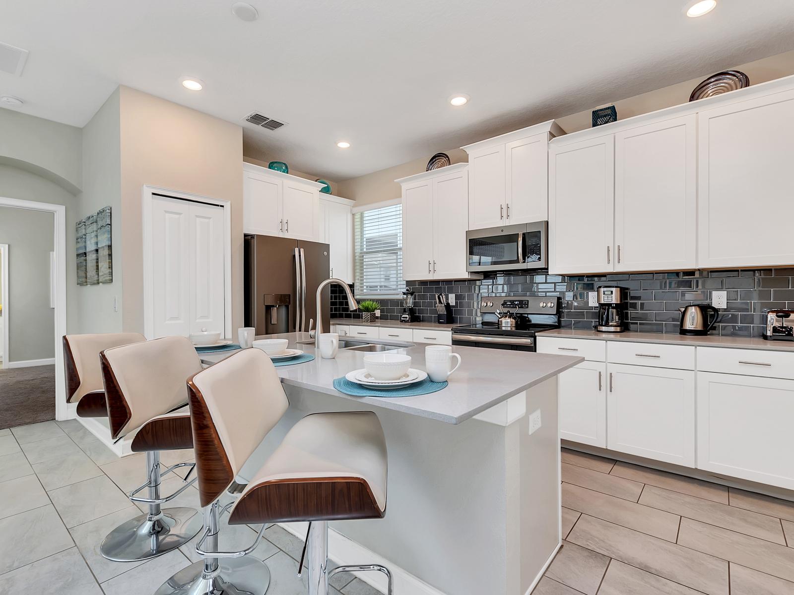 Modern Kitchen of the Home in Davenport Florida - Experience the epitome of sophistication in kitchen area - Refined design meets functionality - Stainless Steel appliances - High Chairs and Breakfast Bar