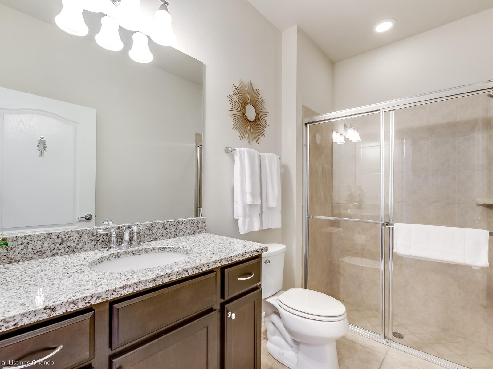 Lavish Bathroom of the apartment in Kissimmee - Beautiful Vanity with large size wall mirror - Sufficient storage space - Neat and clean toilet seat - Availability of all bathroom amenities - Stunning glass cabin shower area