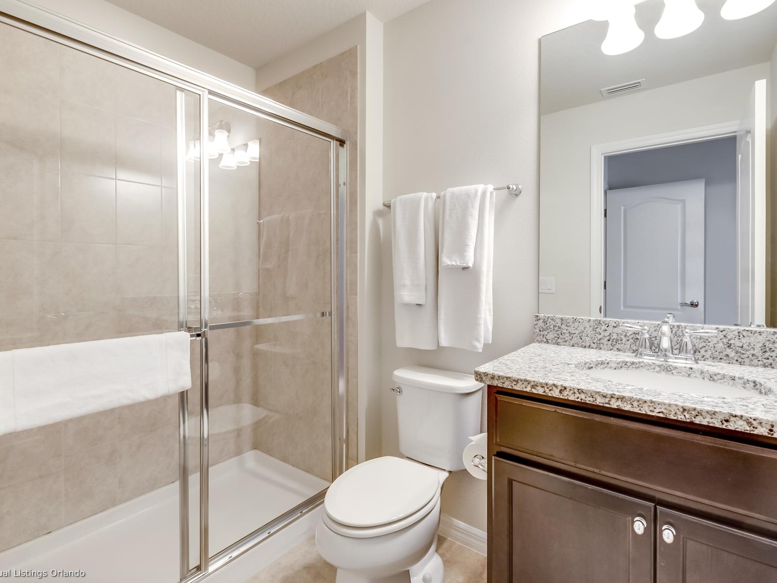 Classy Bathroom of the apartment in Kissimmee - Beautiful Vanity with large size wall mirror - Sufficient storage space - Neat and clean toilet seat - Availability of all bathroom amenities - Stunning glass cabin shower area