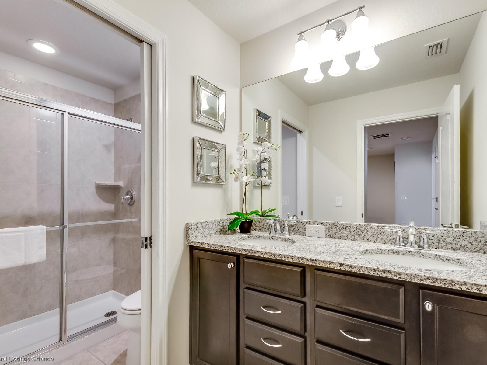 Lavish Bathroom of the apartment in Kissimmee - Beautiful Vanity with large size wall mirror - Sufficient storage space - Neat and clean toilet seat - Availability of all bathroom amenities - Stunning glass cabin shower area