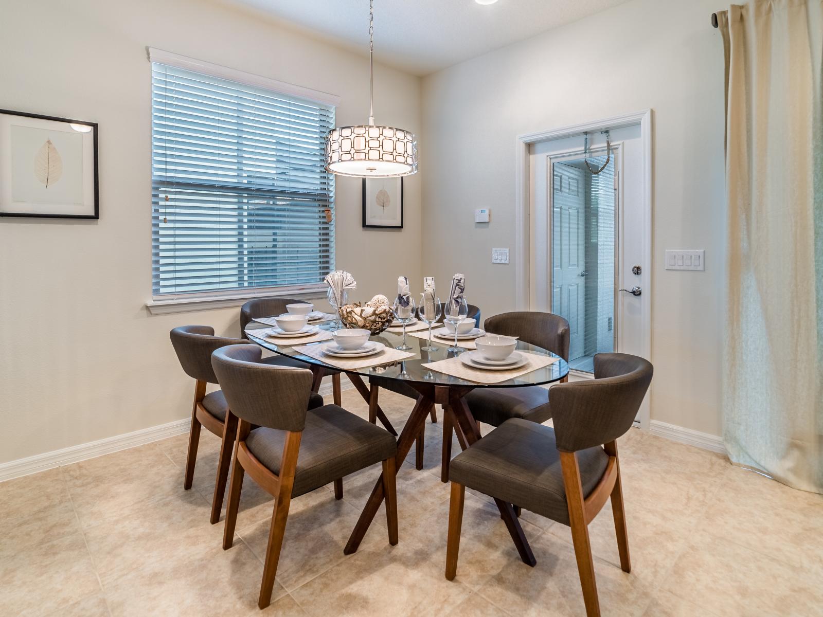 Charming dining area of the  townhouse in Kissimmee, Florida - Elegant dining area offers 6 persons seating with statement chandelier and table setting - Natural light in the dining area creating a bright and airy atmosphere for enjoying meals