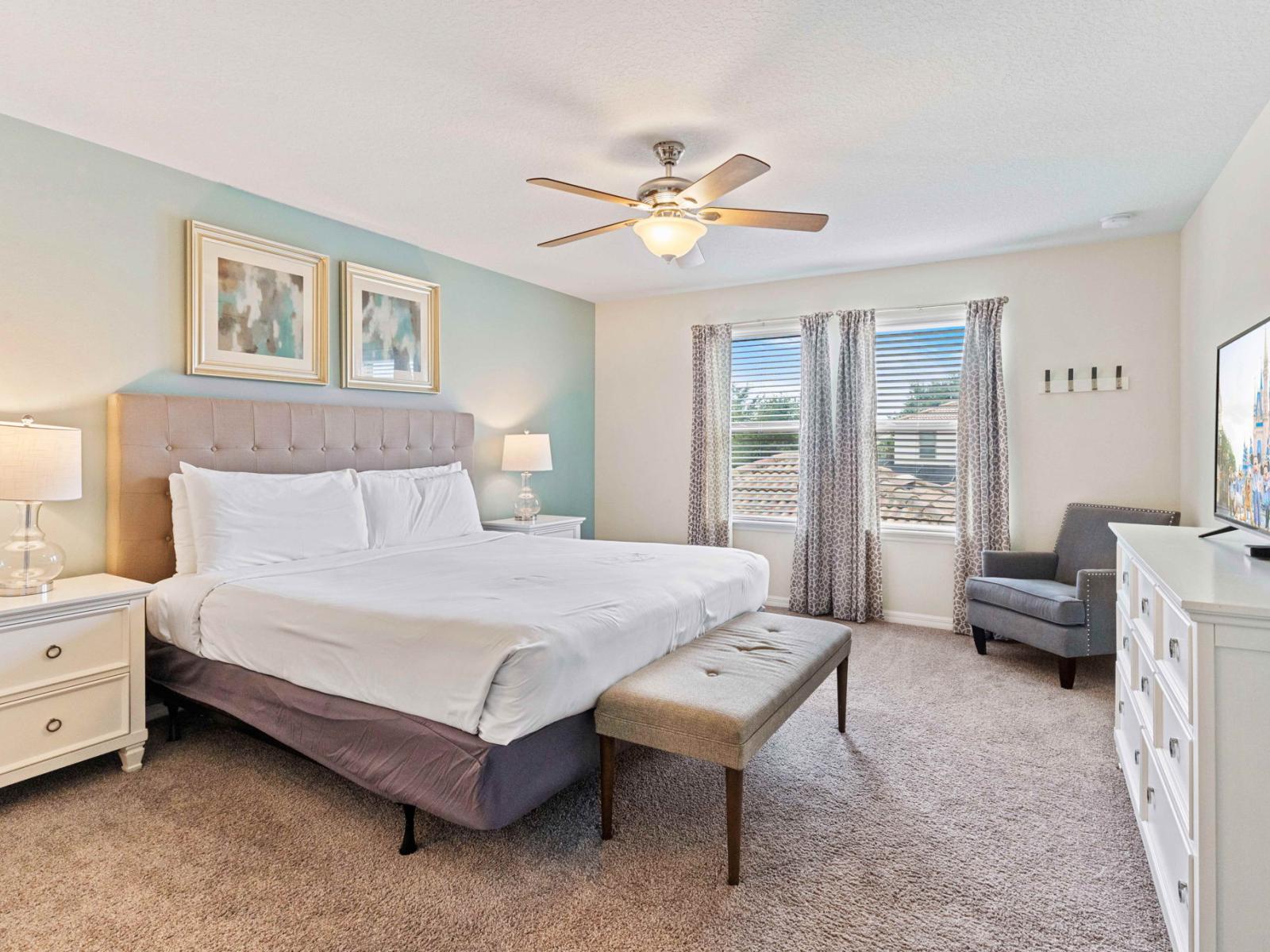 The main bedroom boasts a king-size bed, ensuite bathroom, ceiling fan, and smart TV, creating a luxurious retreat where indulgence meets convenience, promising nights of unparalleled comfort and relaxation.