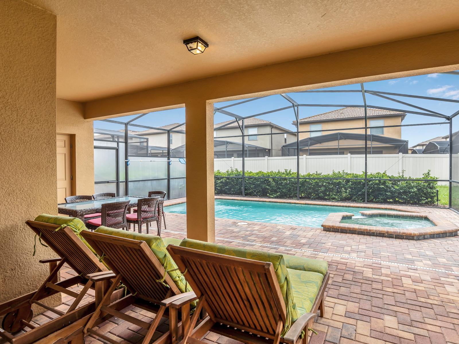 Step into relaxation: Our private screened-in lanai invites you to unwind with a patio table, lounge chairs, and a sparkling pool.