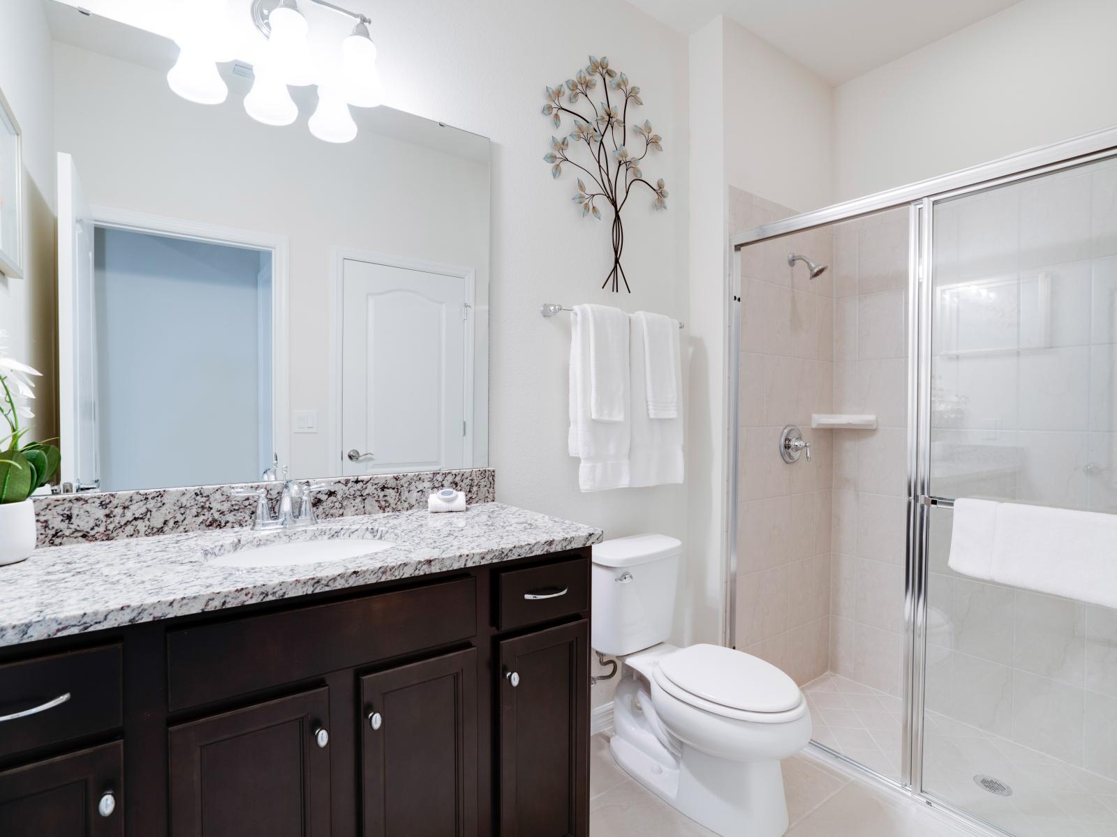 Classy Bathroom of the apartment in Kissimmee - Beautiful Vanity with large size wall mirror - Sufficient storage space - Neat and clean toilet seat - Availability of all bathroom amenities - Stunning glass cabin shower area