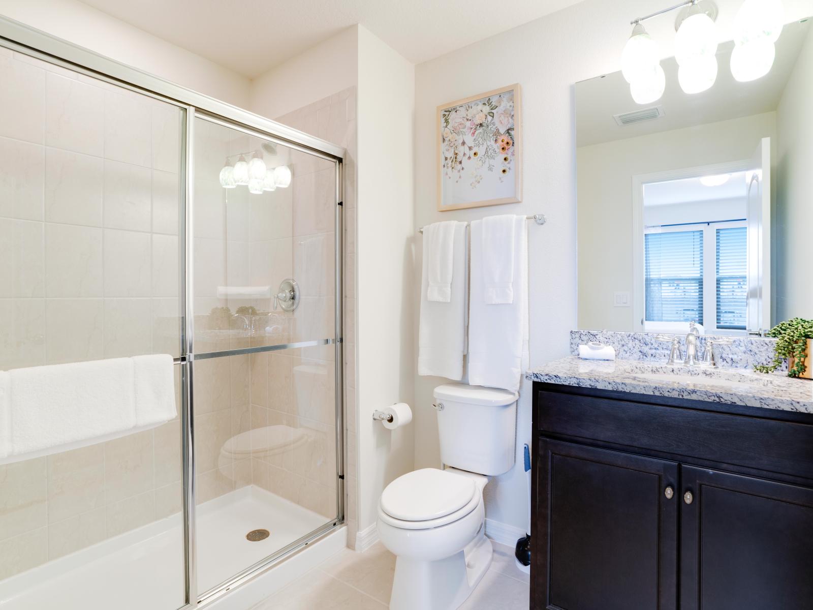 High-class Bathroom of the apartment in Kissimmee - Beautiful Vanity with large size wall mirror - Sufficient storage space - Neat and clean toilet seat - Availability of all bathroom amenities - Stunning glass cabin shower area