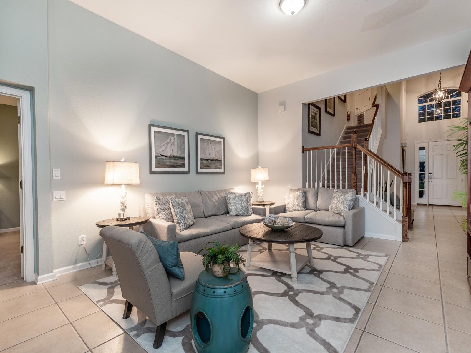 Curl up and unwind in our cozy living room, nestled conveniently near the staircase for easy access to the upper levels, offering comfort and relaxation.