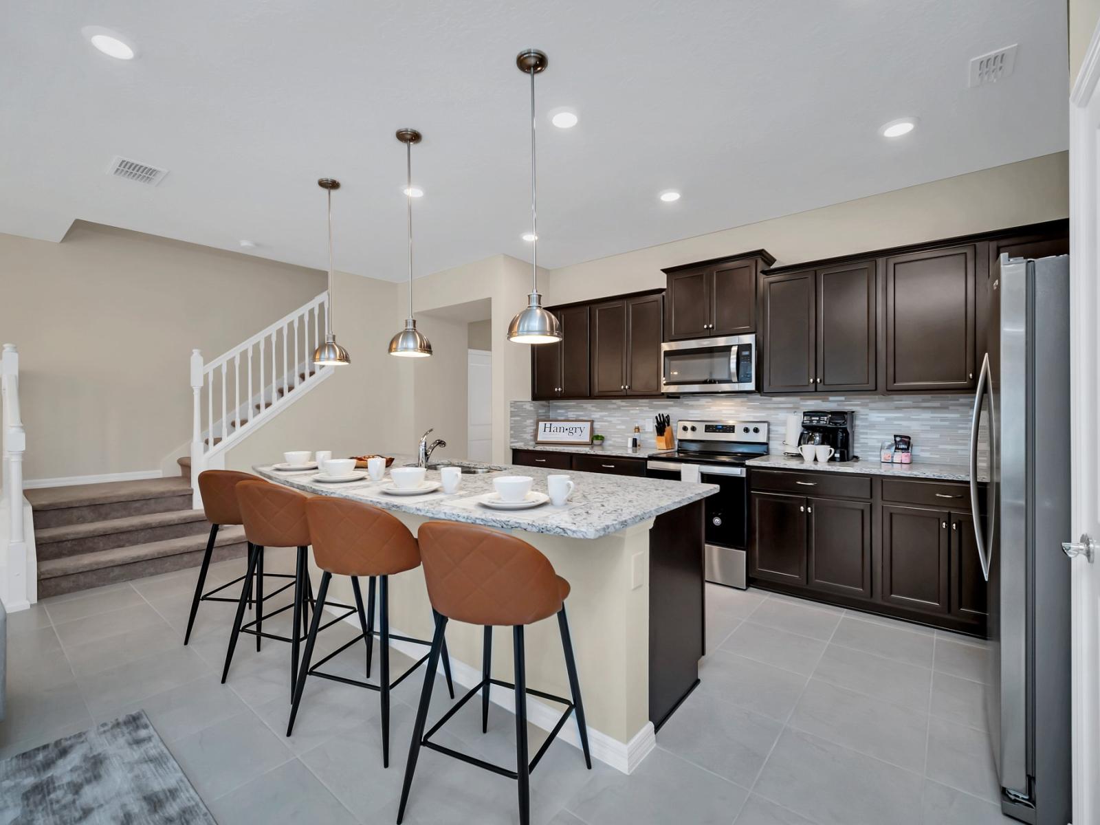 Spacious kitchen of the townhouse in Polk County, Florida - Contemporary open concept Kitchen with countertop and high chairs - Fully equipped with modern appliances - Selectively chosen lighting fixtures that bring both functionality and charm