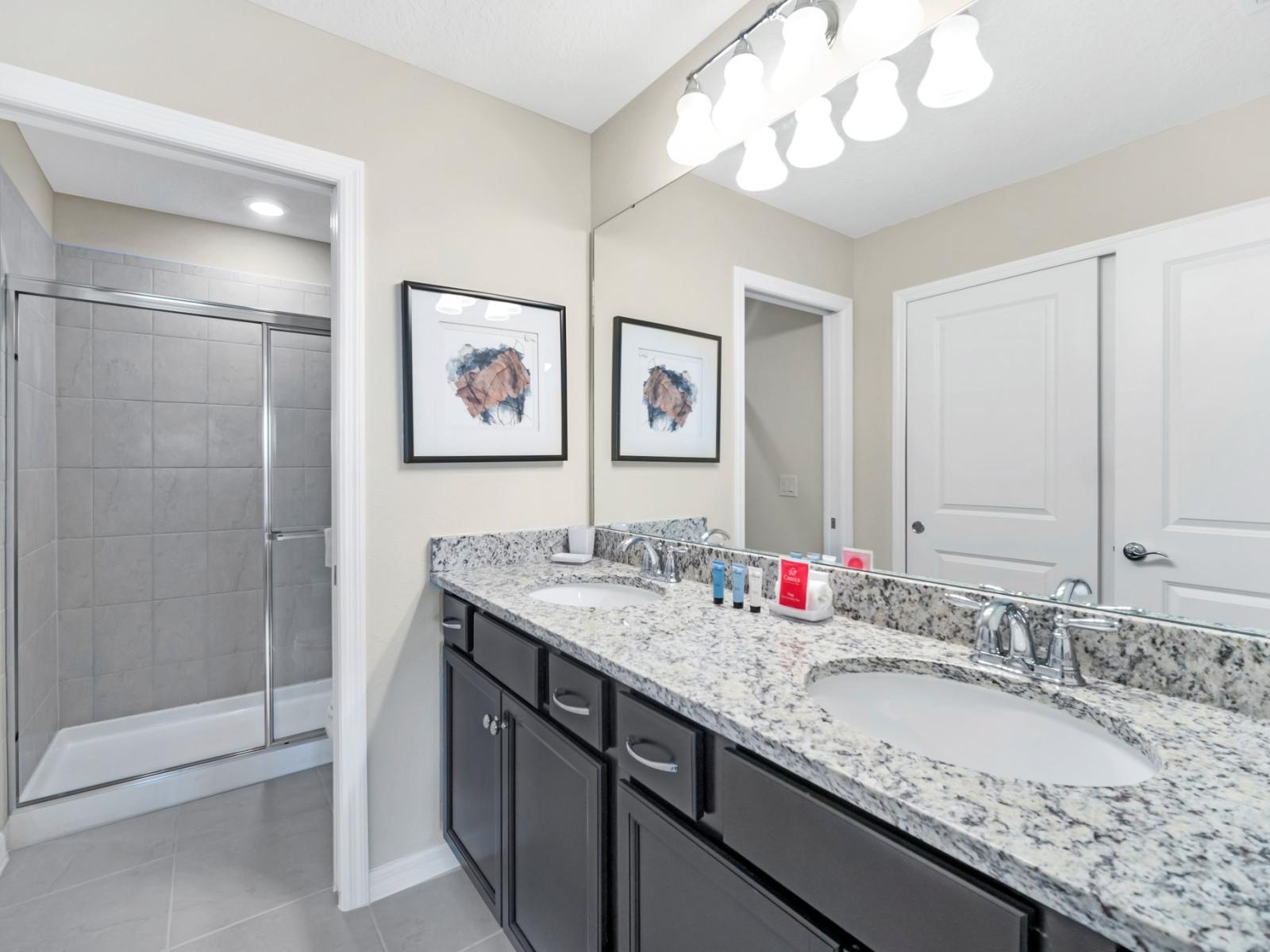 Sleek bathroom of the townhouse in Polk County, Florida - Gorgeous vanity complemented by a spacious wall mirror - Impeccably pristine toilet seat - Complete array of luxurious bathroom essentials - Breathtaking glass-enclosed shower enclosure