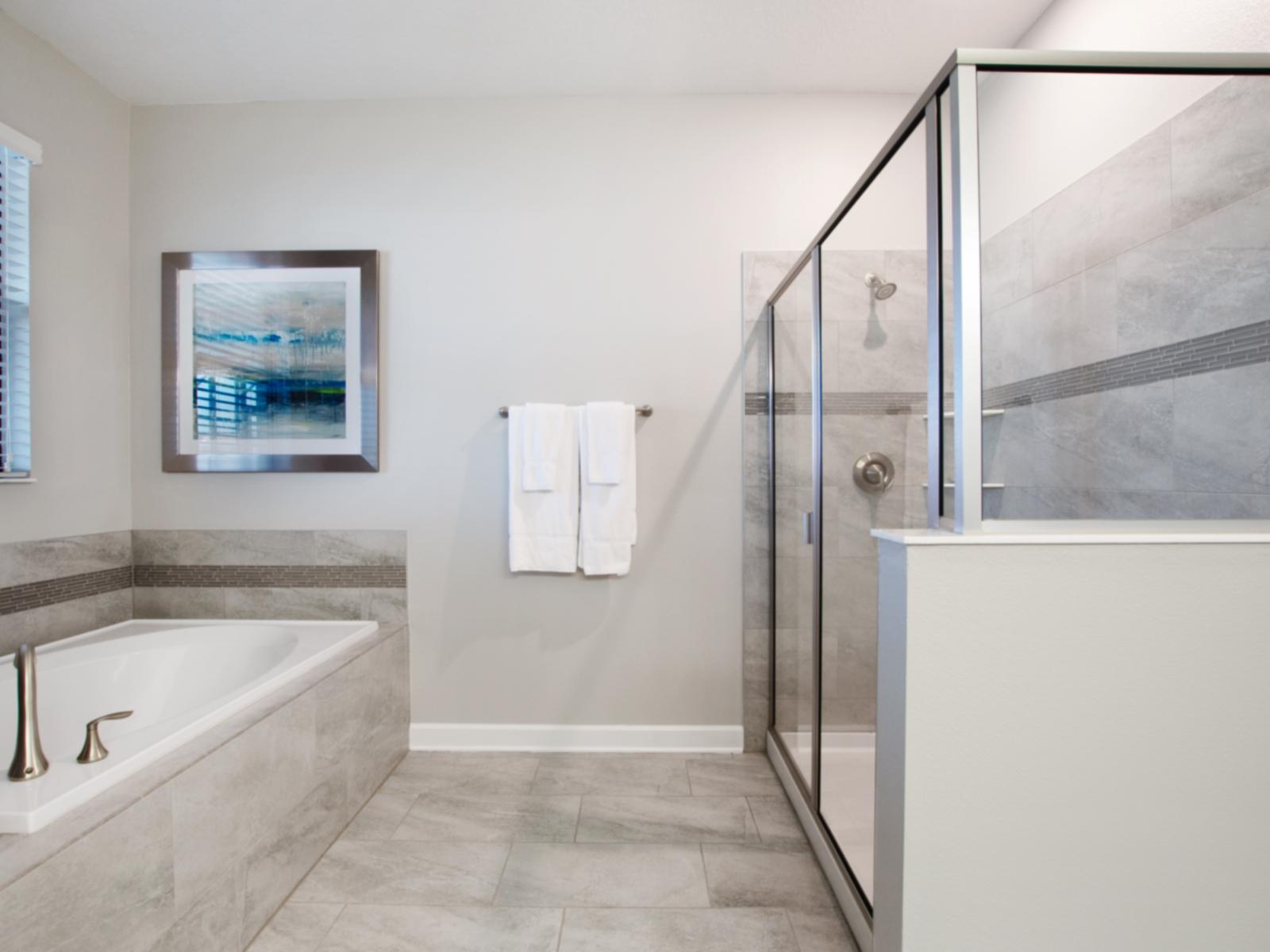 Polished Bathroom with separate bath tub and glass enclosed shower Area