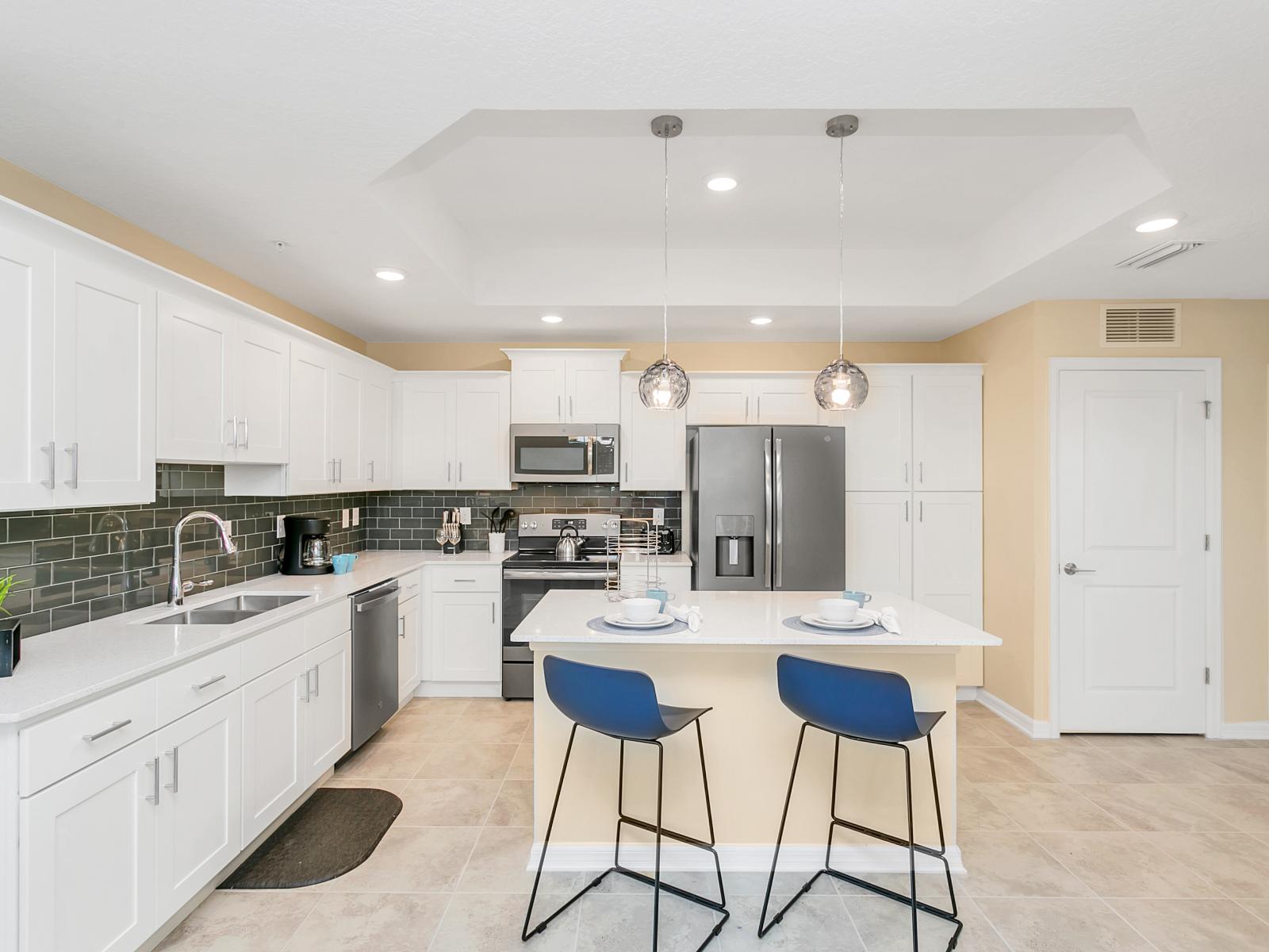 - Spacious open kitchen of the condo in Kissimmee - Thoughtfully designed layout for working ease - Sufficient storage space - Amazing white and badge themed kitchen with elegant lighting - Breakfast bar with cozy high chairs under the focus lamps