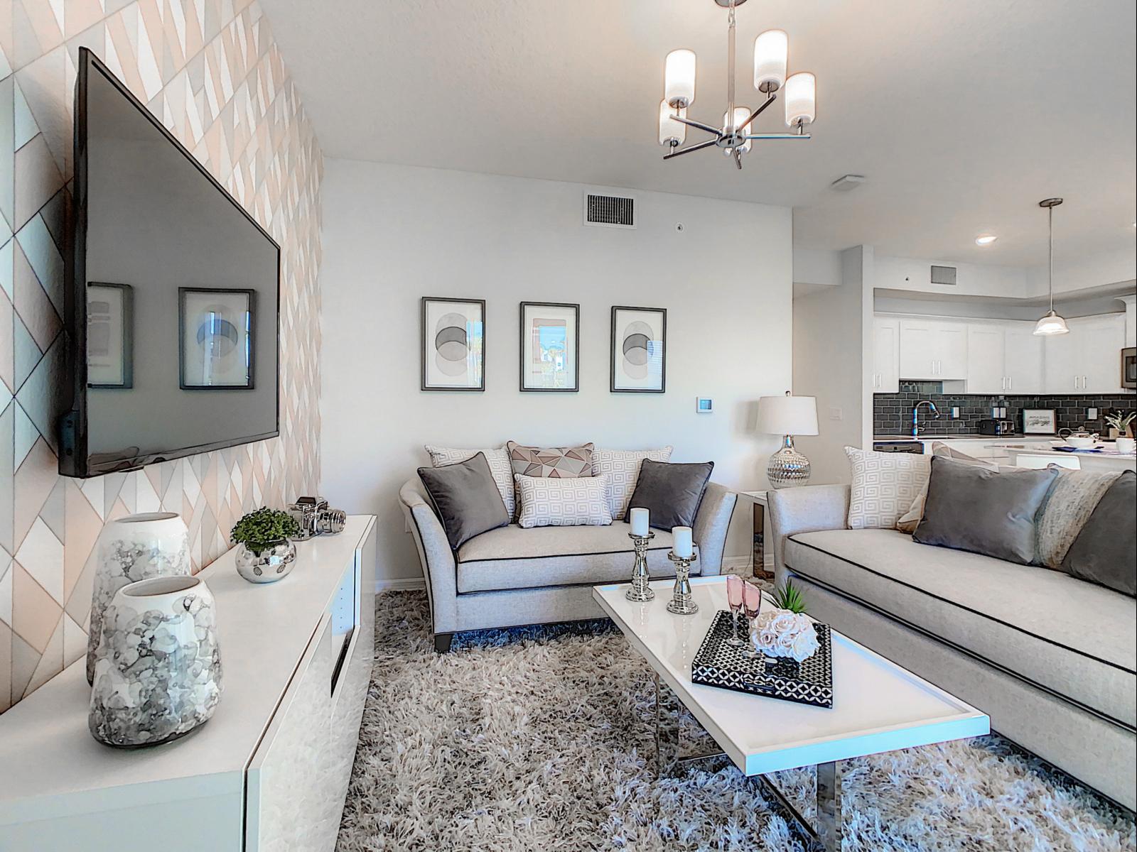 Modern living area where neutral tones meet cozy elegance for a relaxing vibe - Soft decor, warm lighting and plush furnishings make this the perfect spot to unwind - Thoughtful accents and a mounted TV create a space that’s stylish and functional