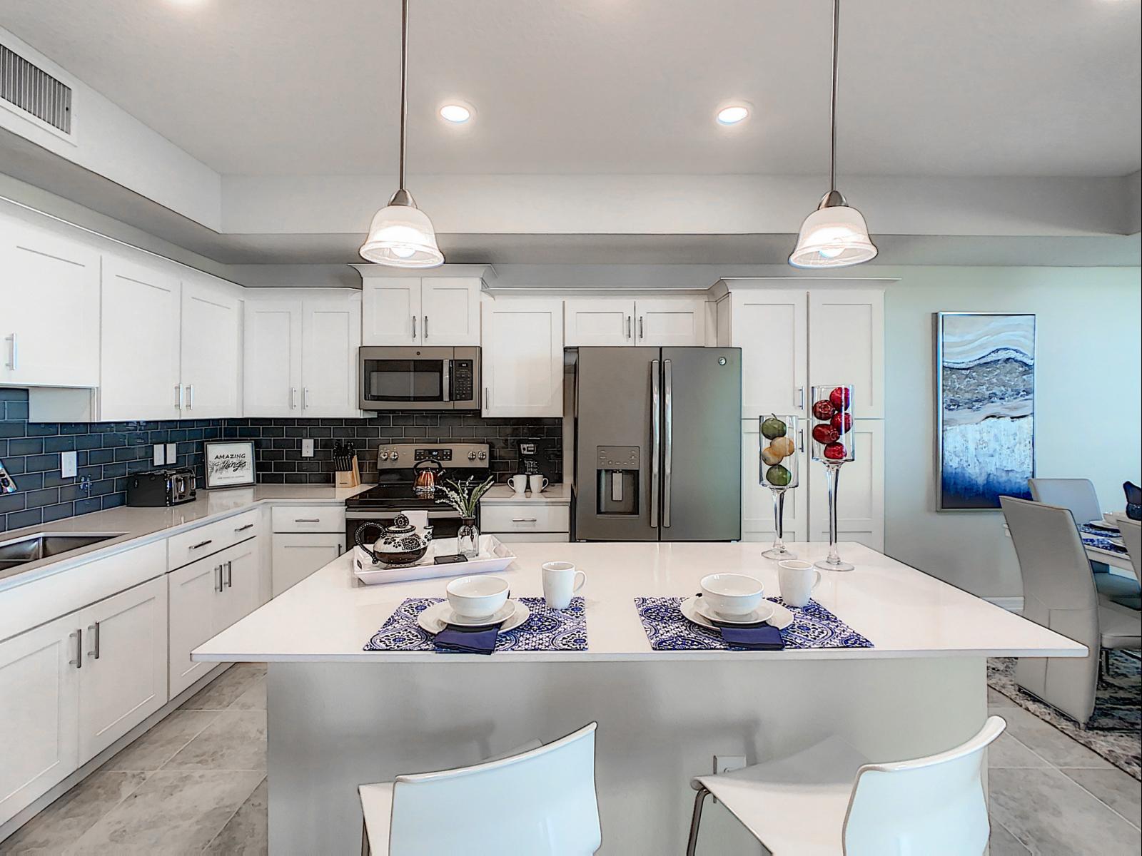 Modern kitchen with a stunning island, ready for culinary creativity or casual bites - Crisp white cabinetry and appliances make this kitchen a dream for any chef - Pendant lighting and thoughtful decor add a touch of sophistication to the space