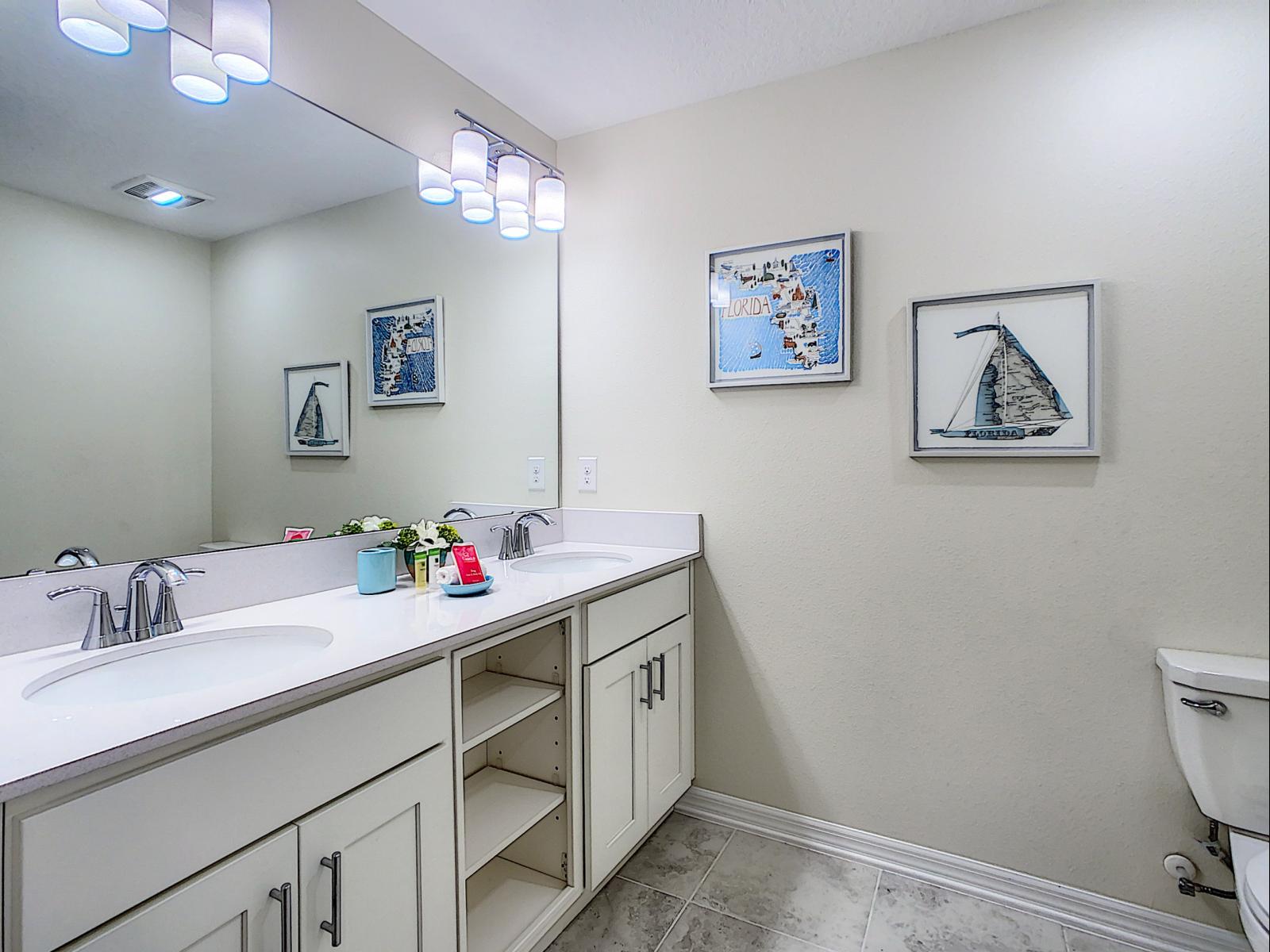 Clean and spacious bathroom with a double vanity, perfect for easy morning routines - Nautical-themed wall art adds a splash of personality and a touch of coastal charm - Extra storage, and soft lighting make this a refreshing space to unwind