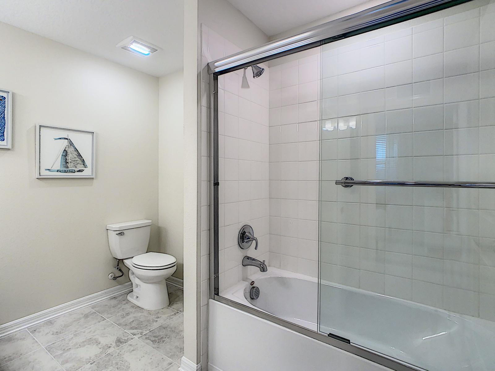 Modern and minimalist bath area with a sparkling glass-enclosed shower for a luxe feel - Relax in this inviting space that balances functionality with style and simplicity - Crisp, clean and thoughtfully designed, ideal for freshening up in comfort