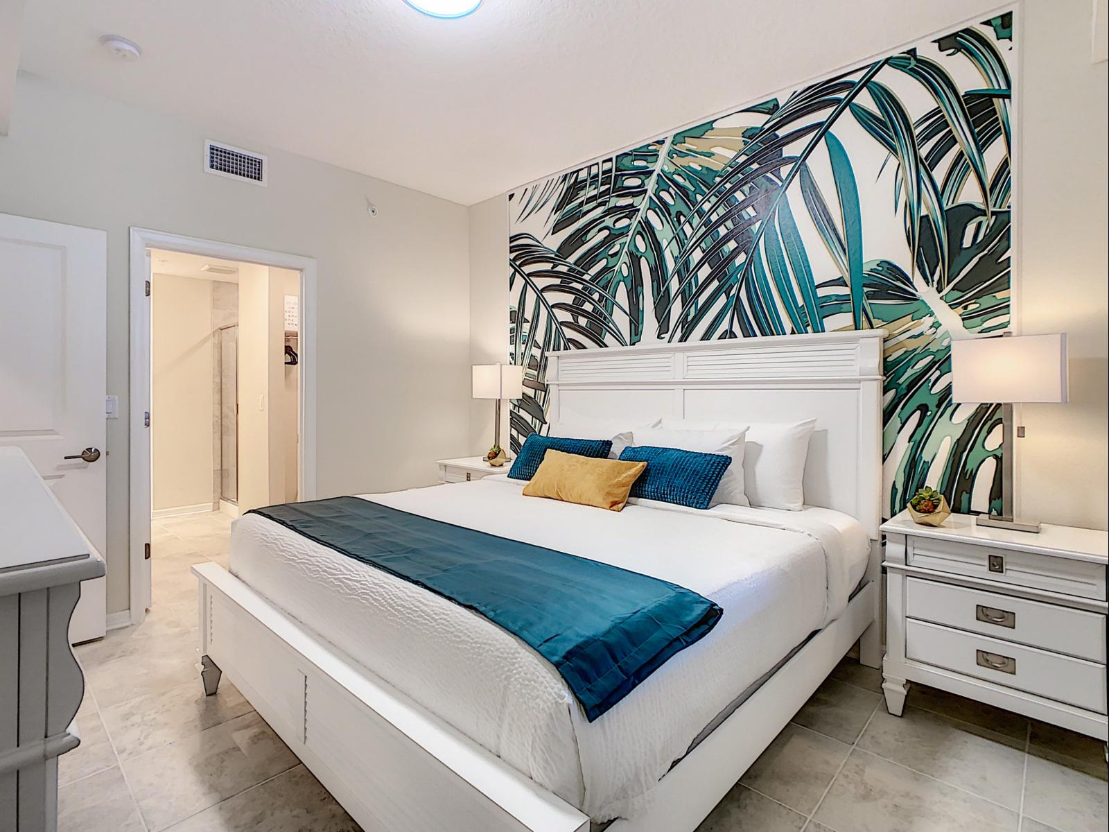 Step into paradise in this tropical-themed bedroom with a palm leaf accent wall - Bright teal accents and cozy bedding create a stylish and serene retreat - Spacious and inviting, it’s the perfect oasis for a restful and peaceful night’s sleep