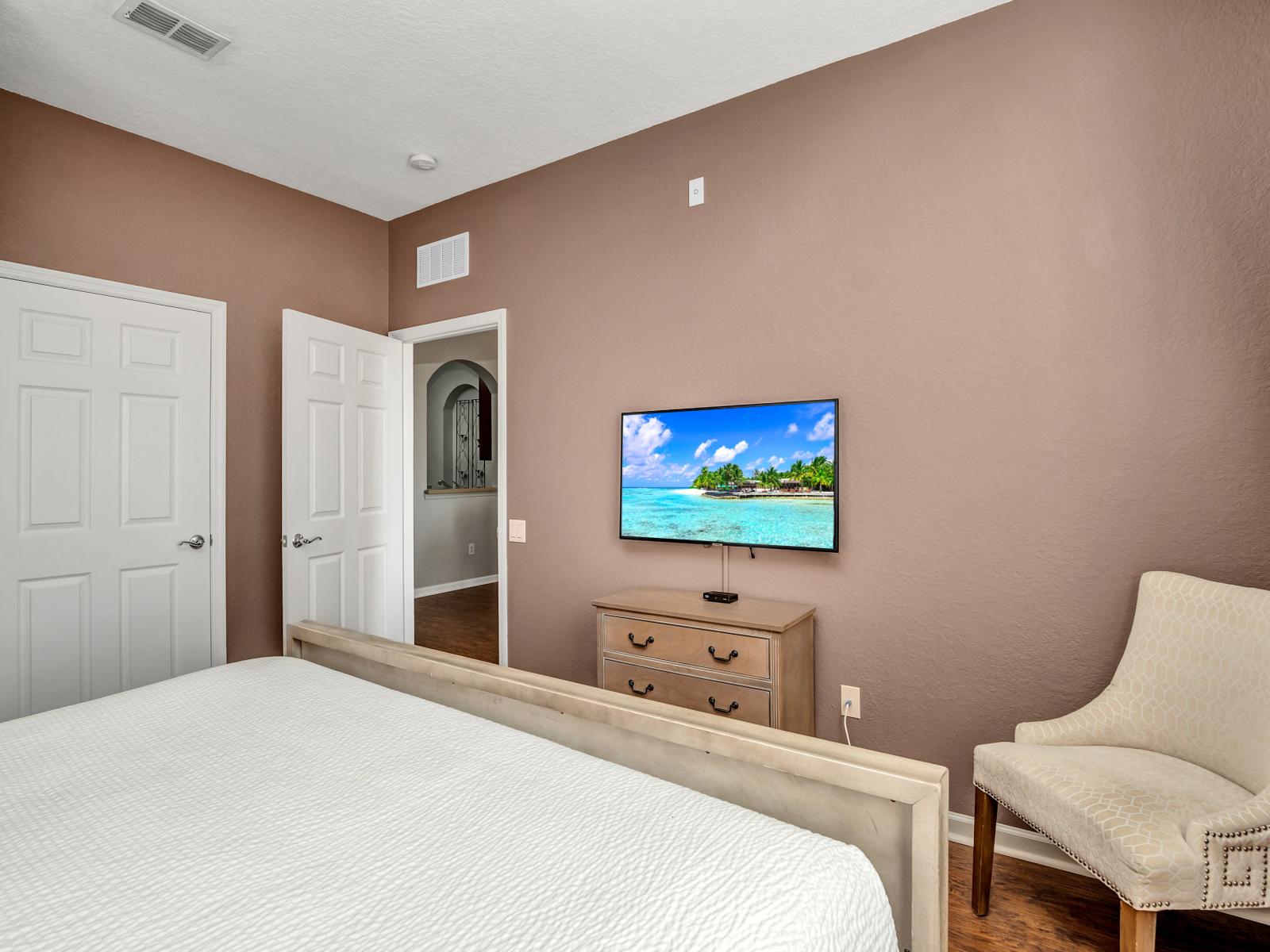 Spectacular bedroom of the condo in Orlando - Featuring a king-size bed and a cozy sofa chair - Marvelously painted walls of the room - Easy convenience of the entertainment with Smart TV - Bright windows with beautiful views