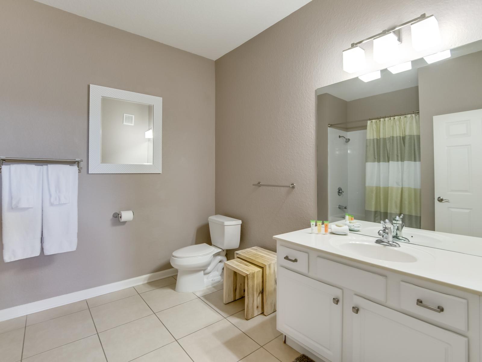 Well-appointed bathroom of the home in Orlando - Neat and clean toilet seat - Availability of fresh towels and all bathroom amenities - stylish vanity with sufficient storage space and wall mirror with elegant lamp