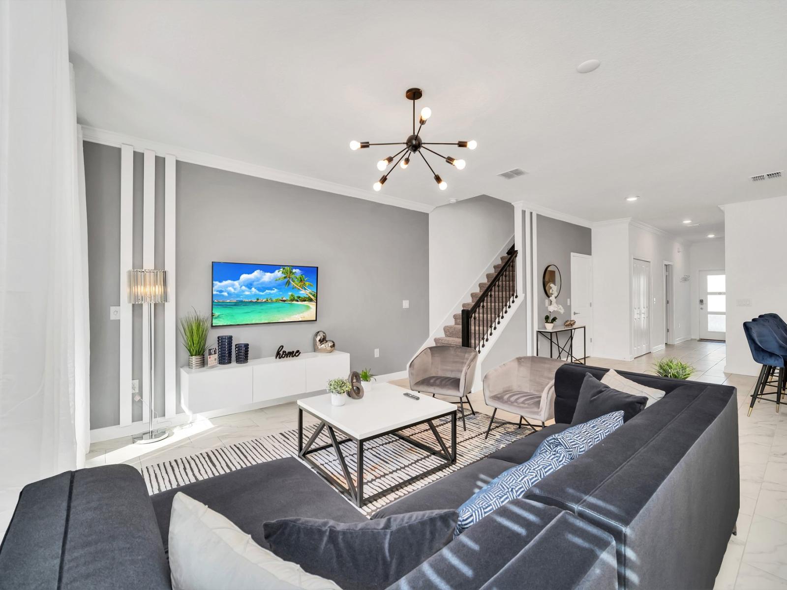 Inviting living area of the townhouse in Kissimmee Florida - Features a comfortable couch and a large flat-screen smart TV - Elegantly decorated space with a neutral color palette for a timeless appeal - Quality fixtures and fittings