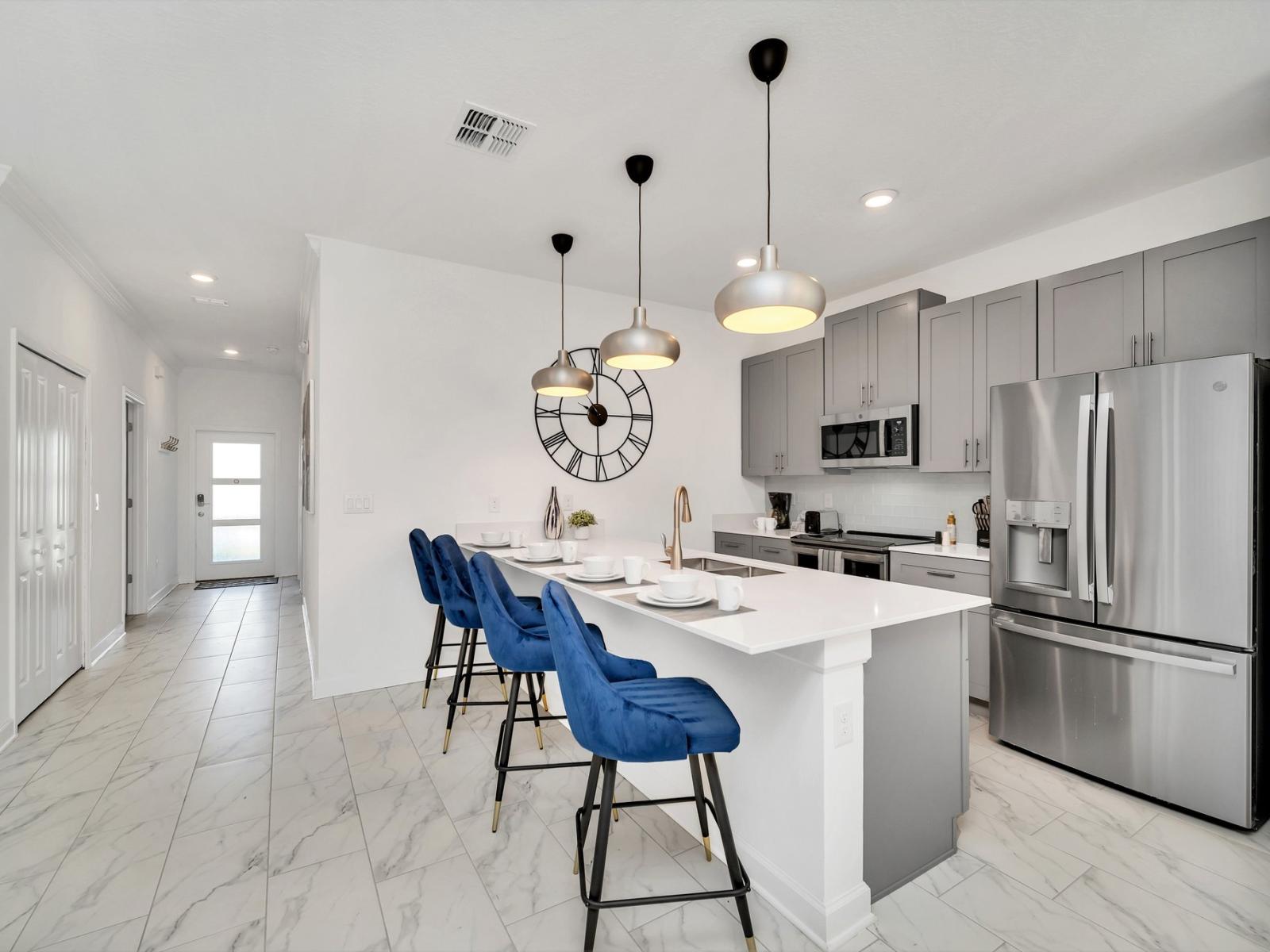 Modern kitchen of the townhouse in Kissimmee Florida - Features a stylish counter table accompanied by sleek blue high chairs - A contemporary and inviting casual dining space within the kitchen - Stainless steel appliances