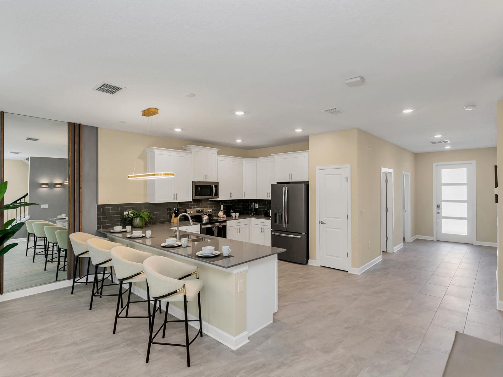 Modern kitchen of the home in Kissimmee Florida - Strategic use of mirrors to enhance the perception of space - Breakfast bar and high chairs - Stainless steel appliances - Thoughtful placement of kitchen essentials for easy access