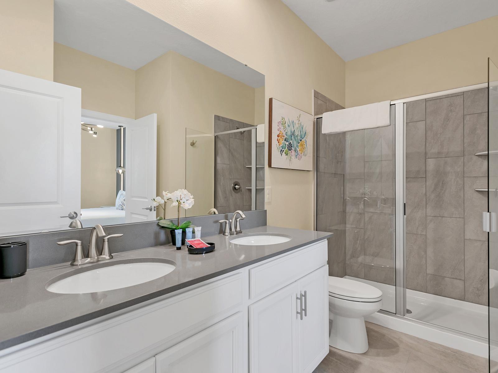 Polished bathroom of the home in Kissimmee Florida - Chic dual vanity with large mirror - Spacious walk-in shower area with glass door - Sophisticated color palette creating a serene ambiance