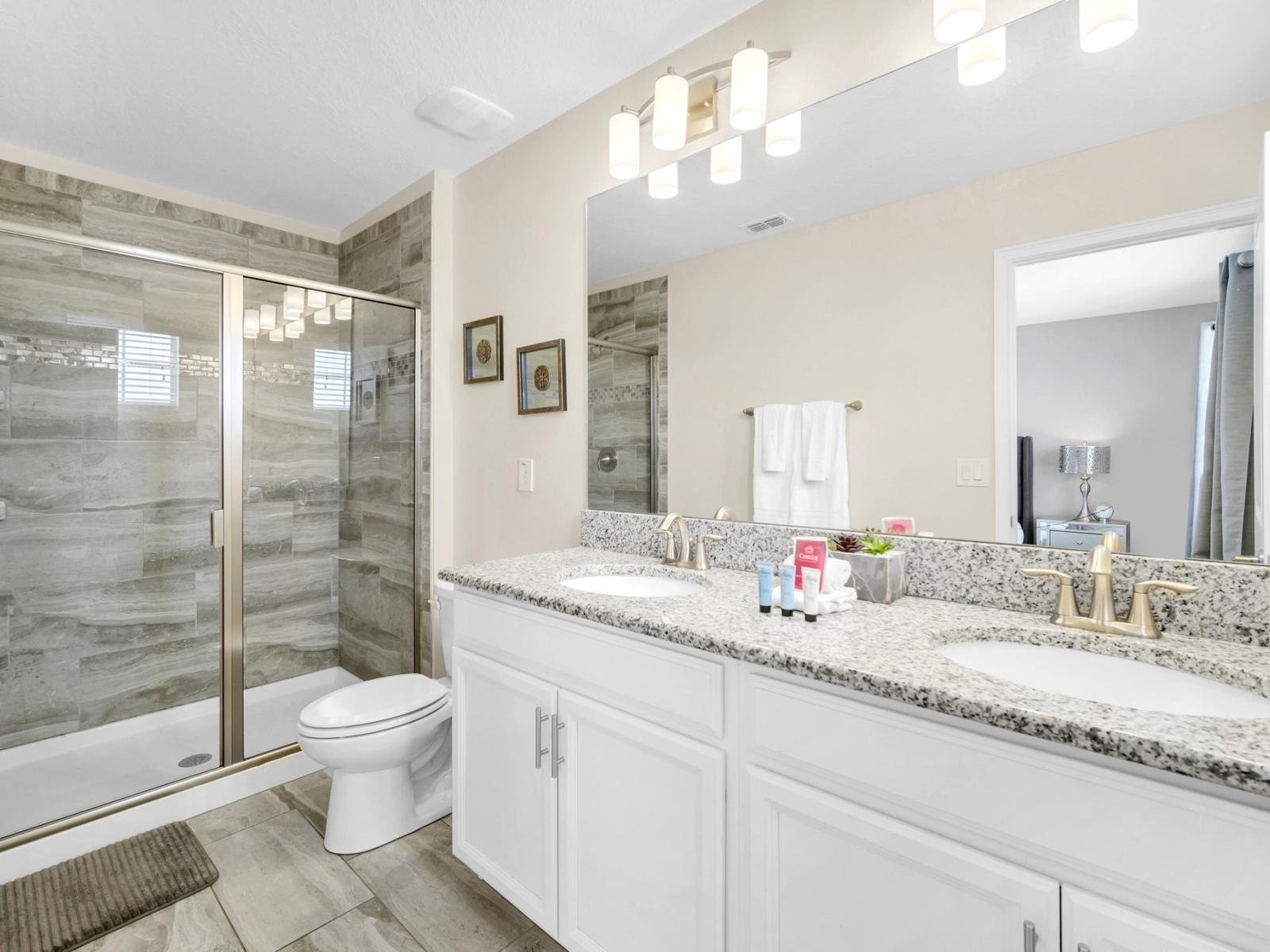 Lavish bathroom of the home in Kissimmee Florida - Modern design with glass-enclose walk-in shower area - Chic design featuring a sleek dual vanity and upscale lighting - Sophisticated color palette creating a serene ambiance