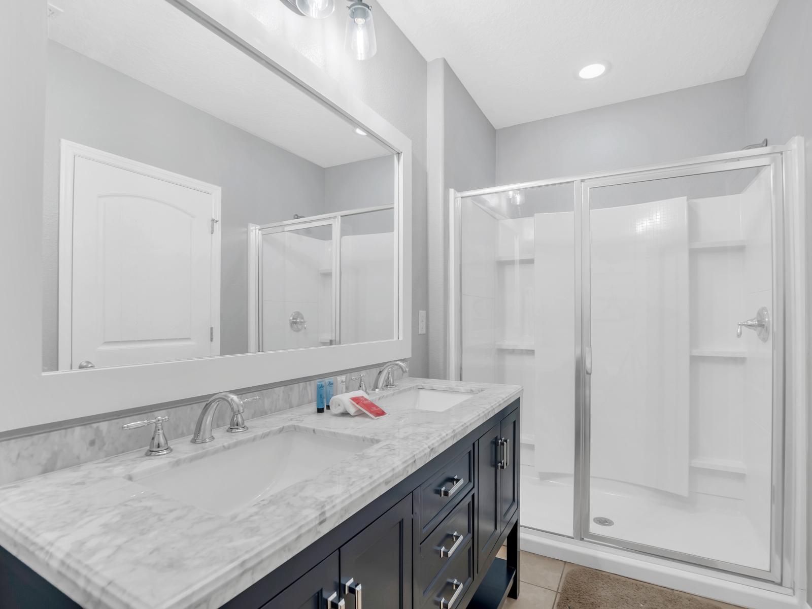 Classy bathroom of the townhouse in Davenport Florida - Beautiful dual vanity with large size wall mirror - Neat and clean toilet seat - Availability of bathroom amenities - Stunning glass cabin shower area