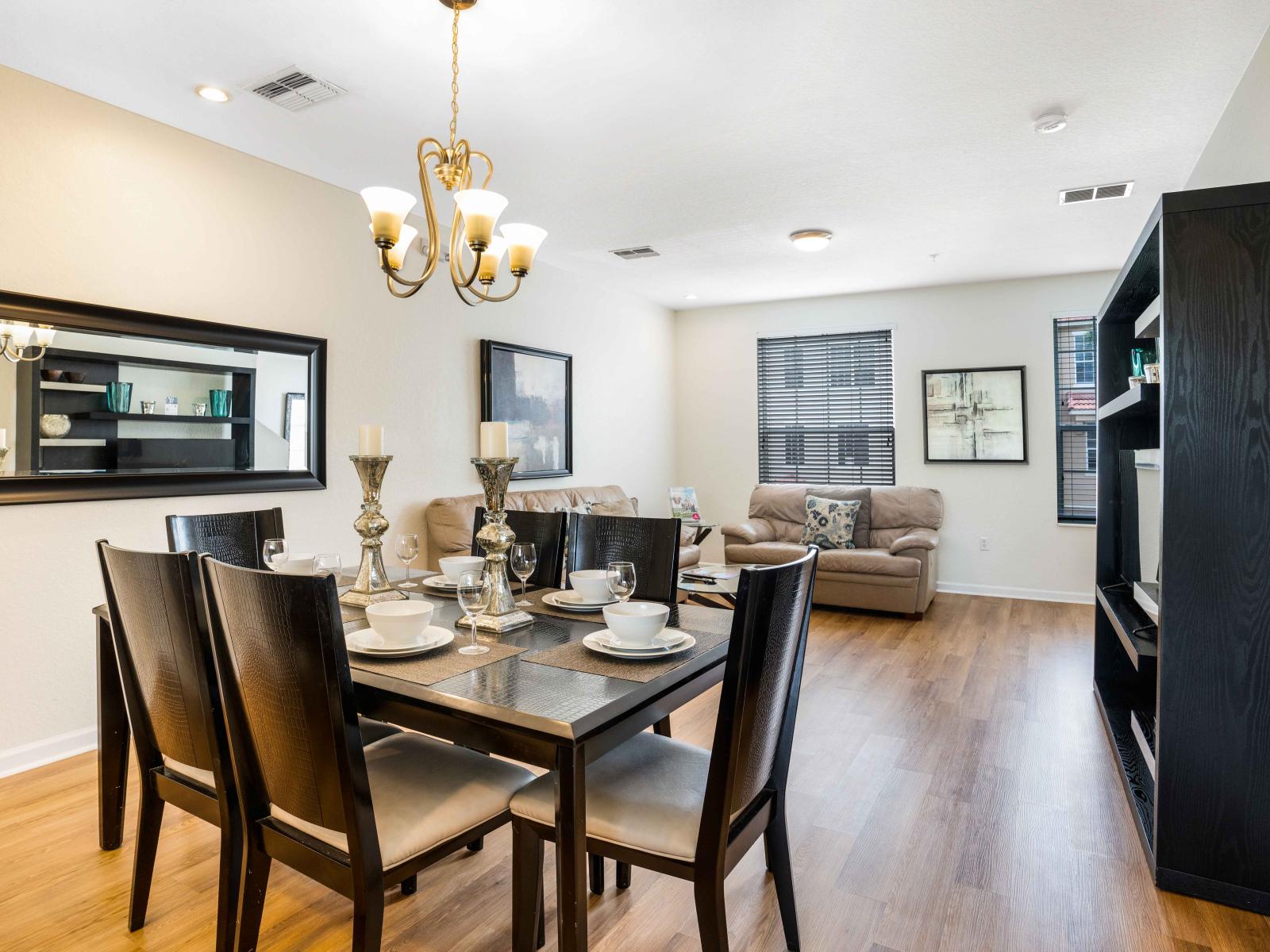 Glamorous dining area of the townhouse in Orlando - Adorned with a sleek black 6 persons dinning table - Creating the perfect ambiance for memorable gatherings and culinary delights.  - Majestic chandelier and wall mirror enhancing the space decor